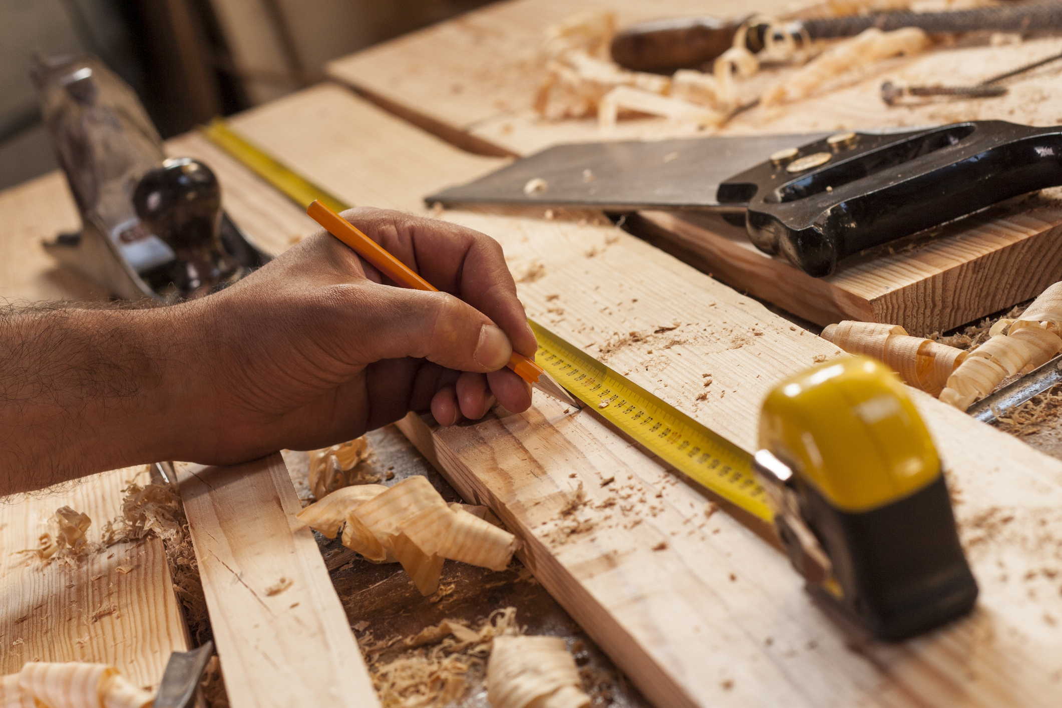 Man using measuring tape on plank of wood