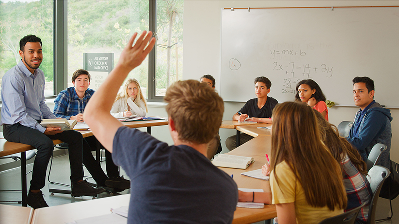 Student raises a hand in a high school classroom