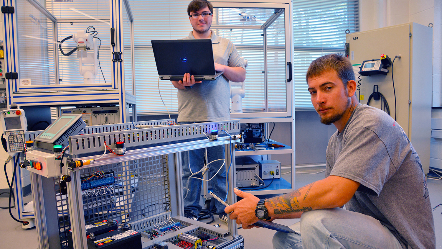 Two students work on machinery in the Mechatronics Lab