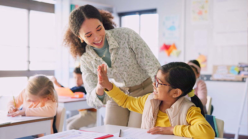 Teacher assists a student with work at her desk