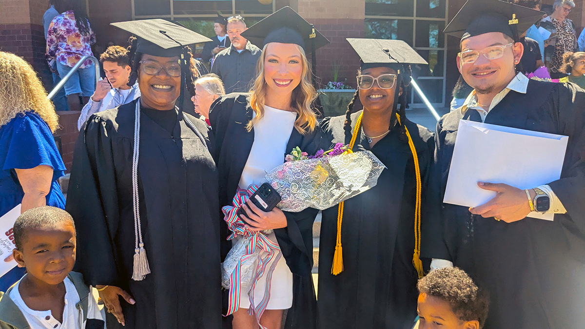 Graduates stand in a group in front of the Cole Auditorium.