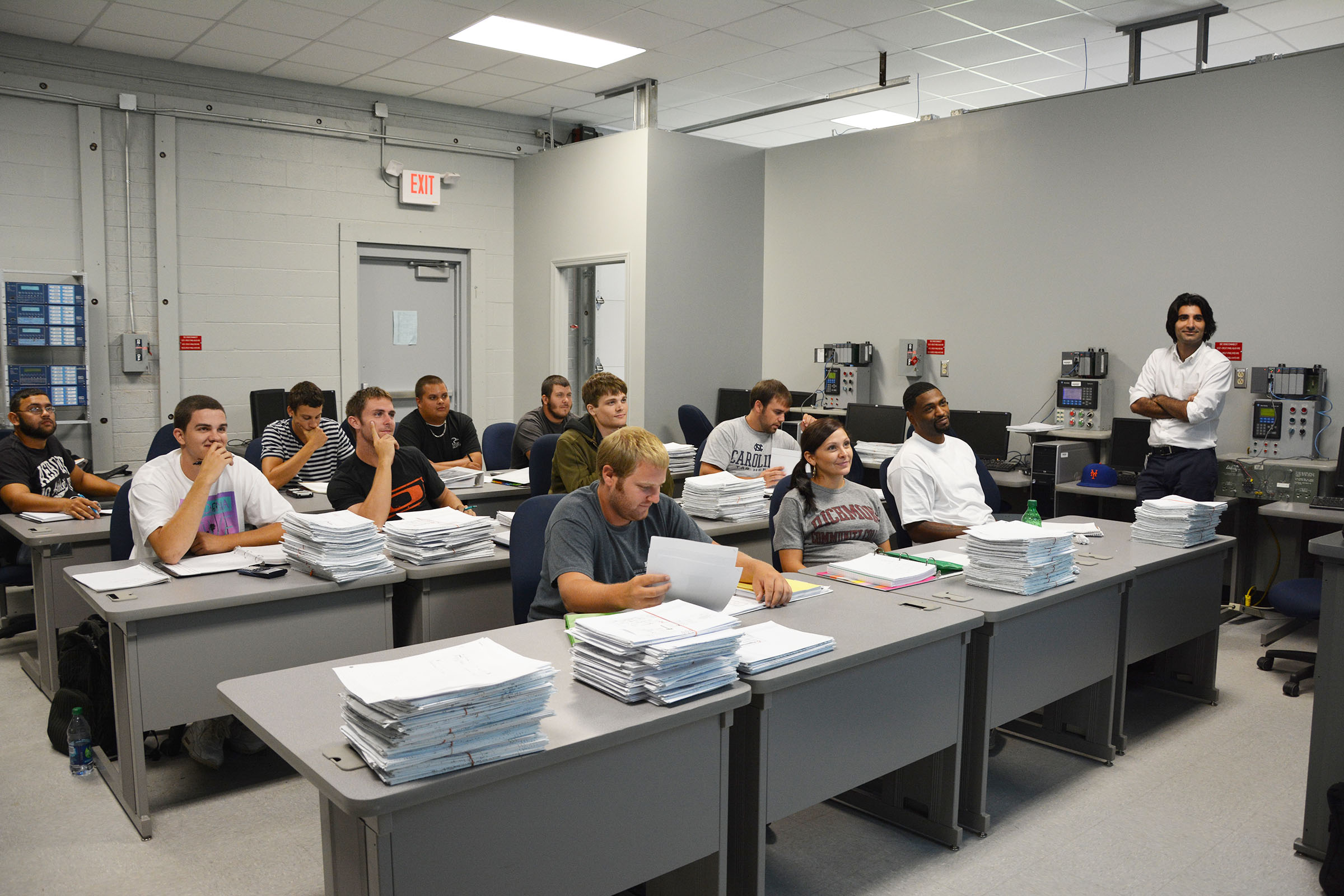 Electric Utility Substation and Relay Technology (EUSRT) instructor Morteza Talebi stands in a classroom with students sitting at desks with books and papers in front of them.