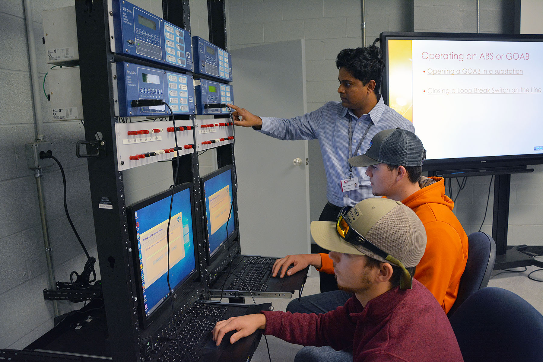 Dr. Rishad Hossain works with two students using Schweitzer relays in a classroom.