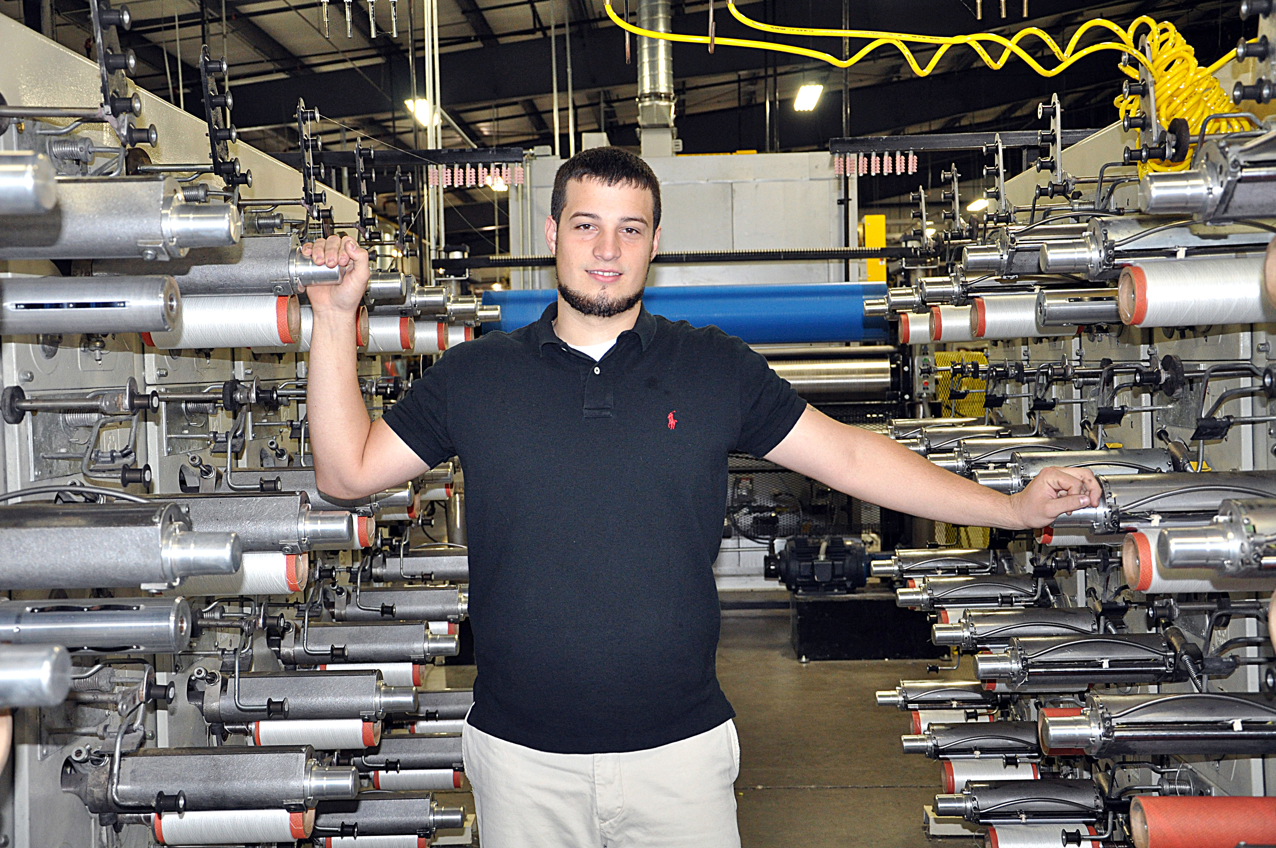 Service Thread employee Jordan Fournier stands with machinery at the company.