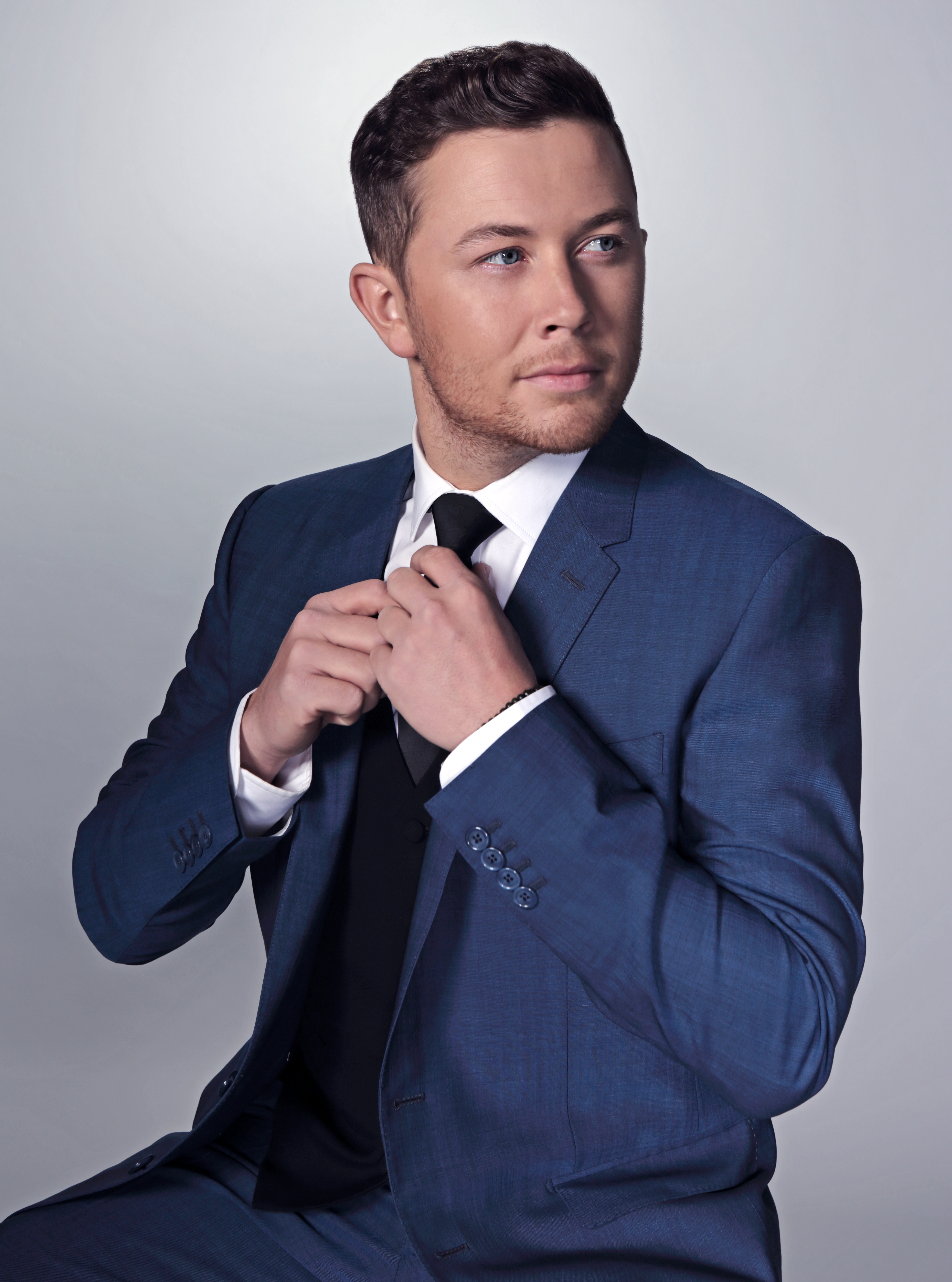 Scotty in a blue suit adjusting his tie