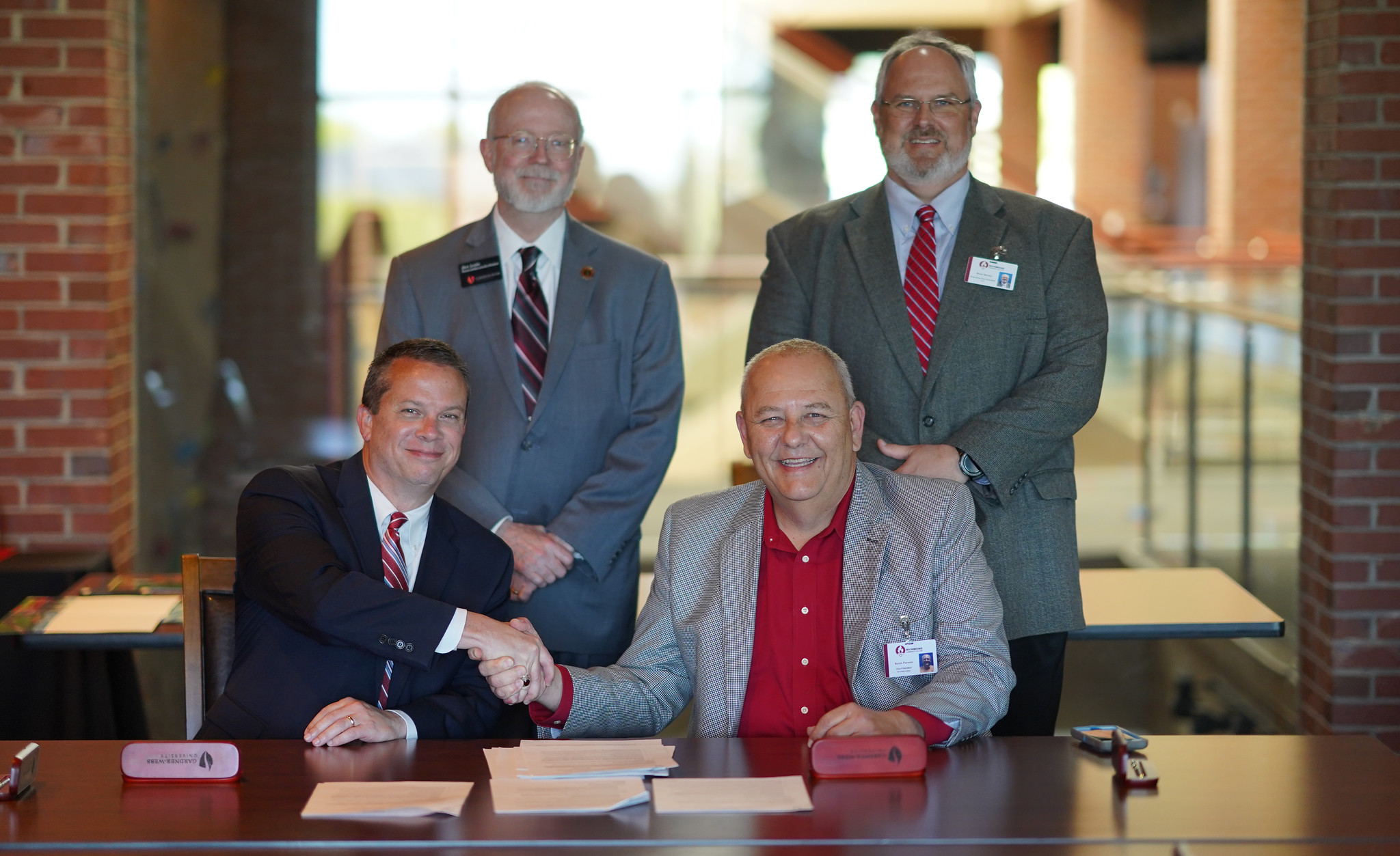 College leaders sit at table and sign articulation agreement