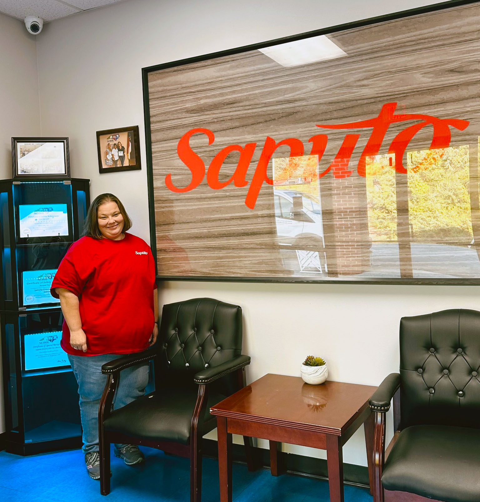 Krista Barfield stands by Saputo sign where she works.