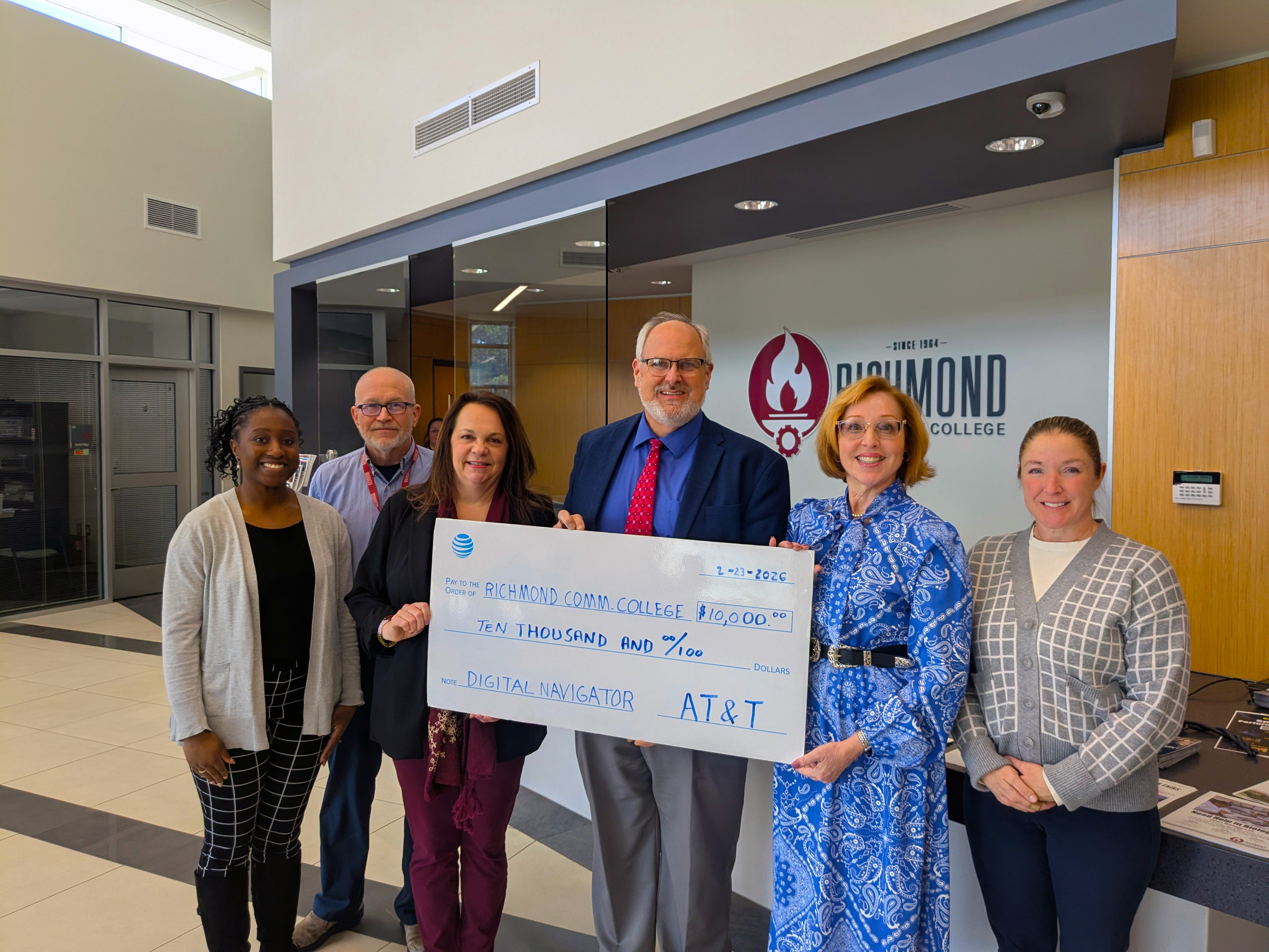 AT&T representative and College staff hold a placard showing the amount of the grant.