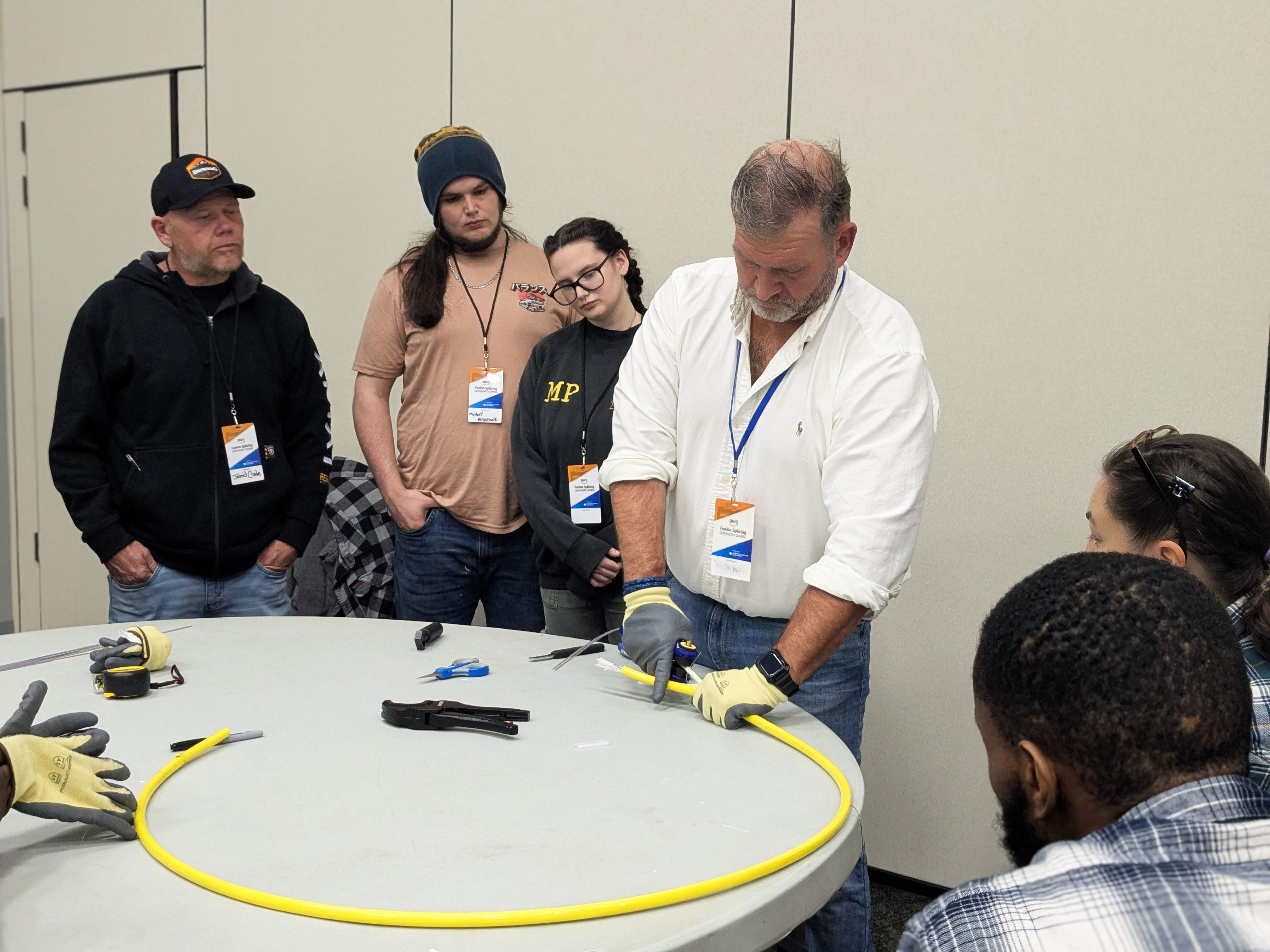 Students watch the instructor working with fiber optic cable.