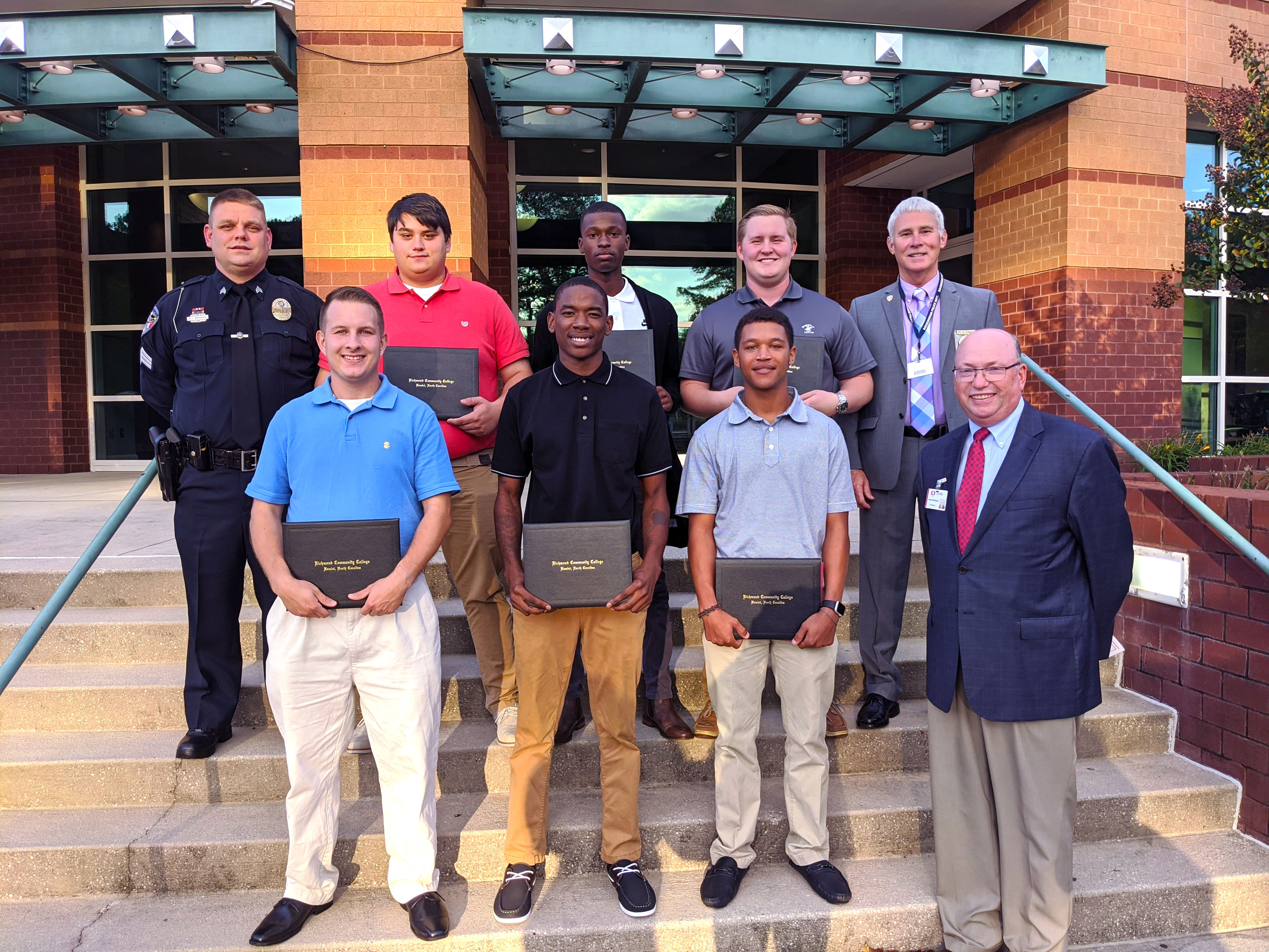 BLET graduates and the training officers stand with Dr. Dale McInnis on the steps of  the Cole Auditorium.