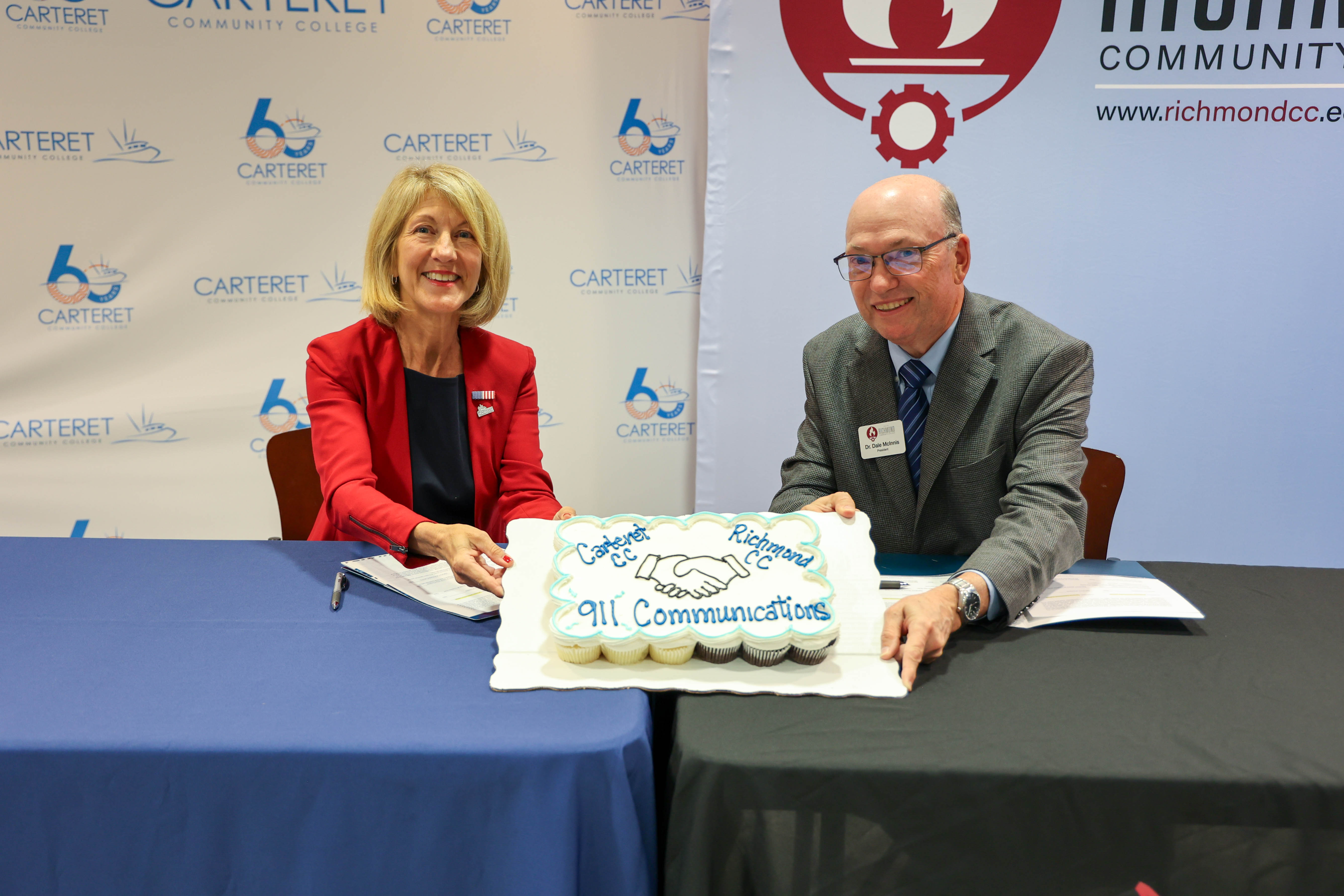 College presidents hold up a sheet cake