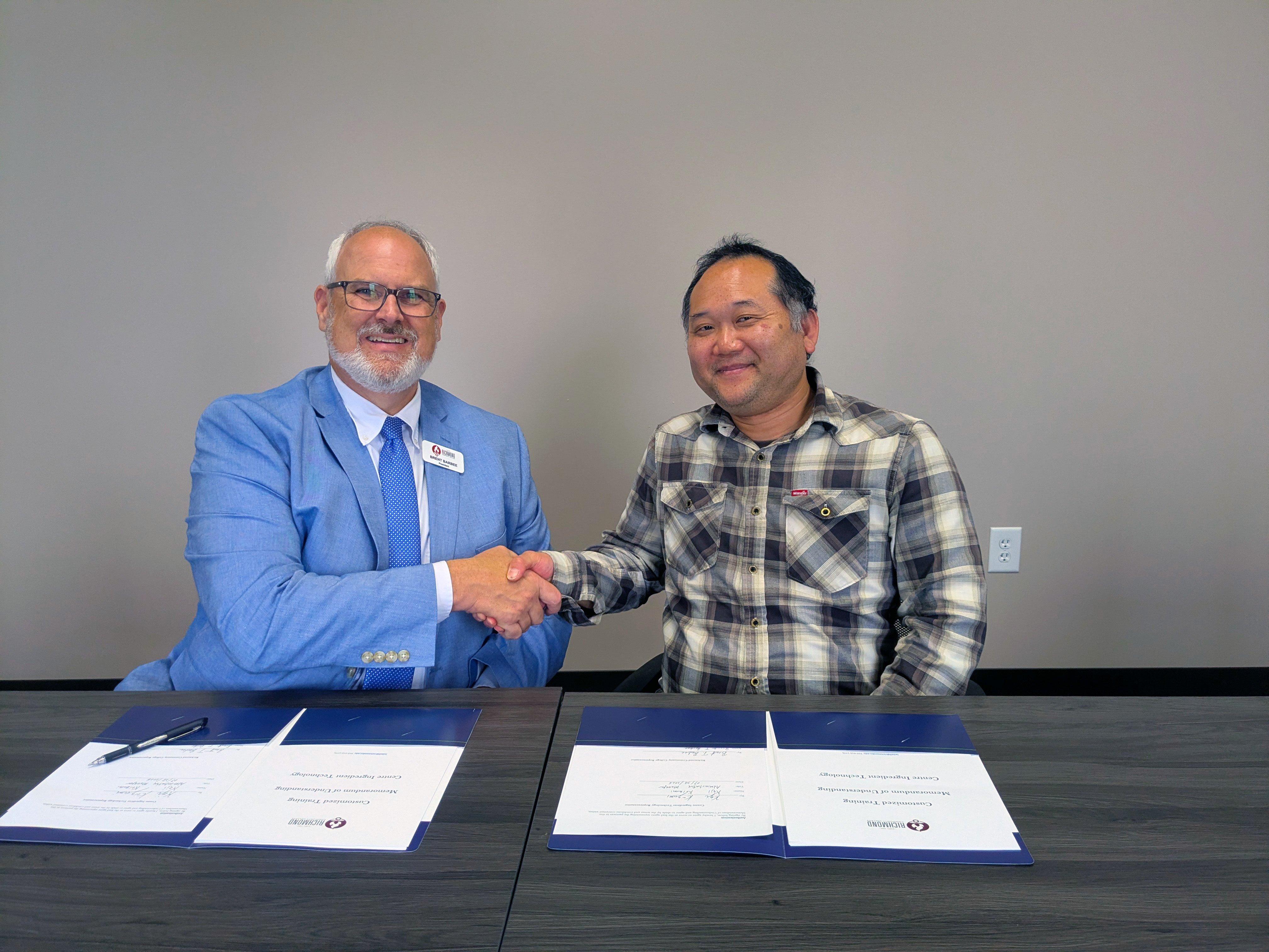 President Barbee and CIT Manager shake hands over paperwork.