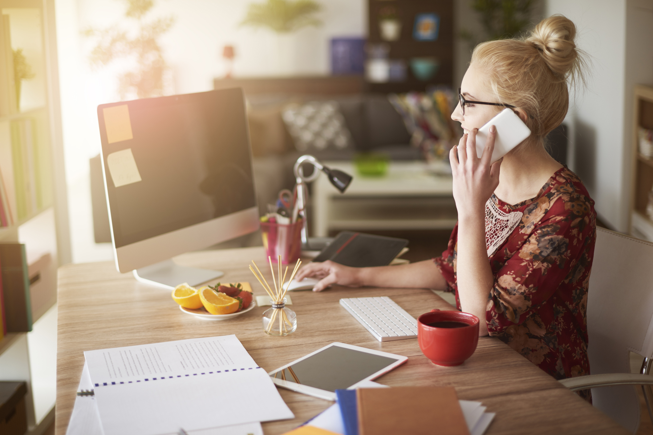 Person holding self phone sitting at home at desk with a computer