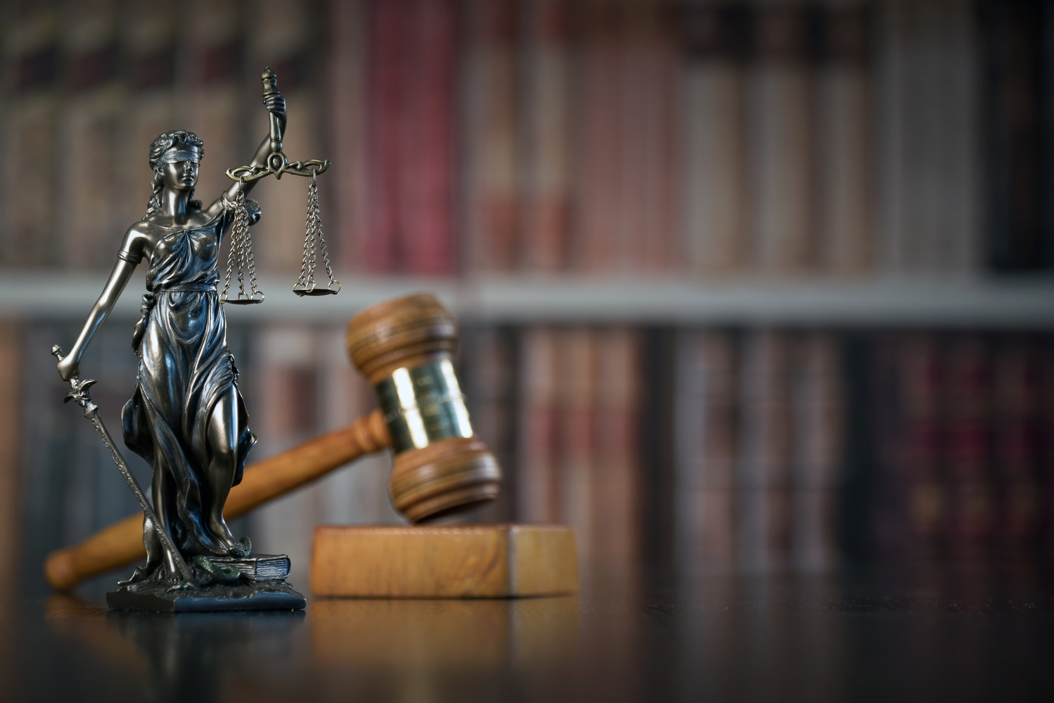Lady justice statue with gavel in background