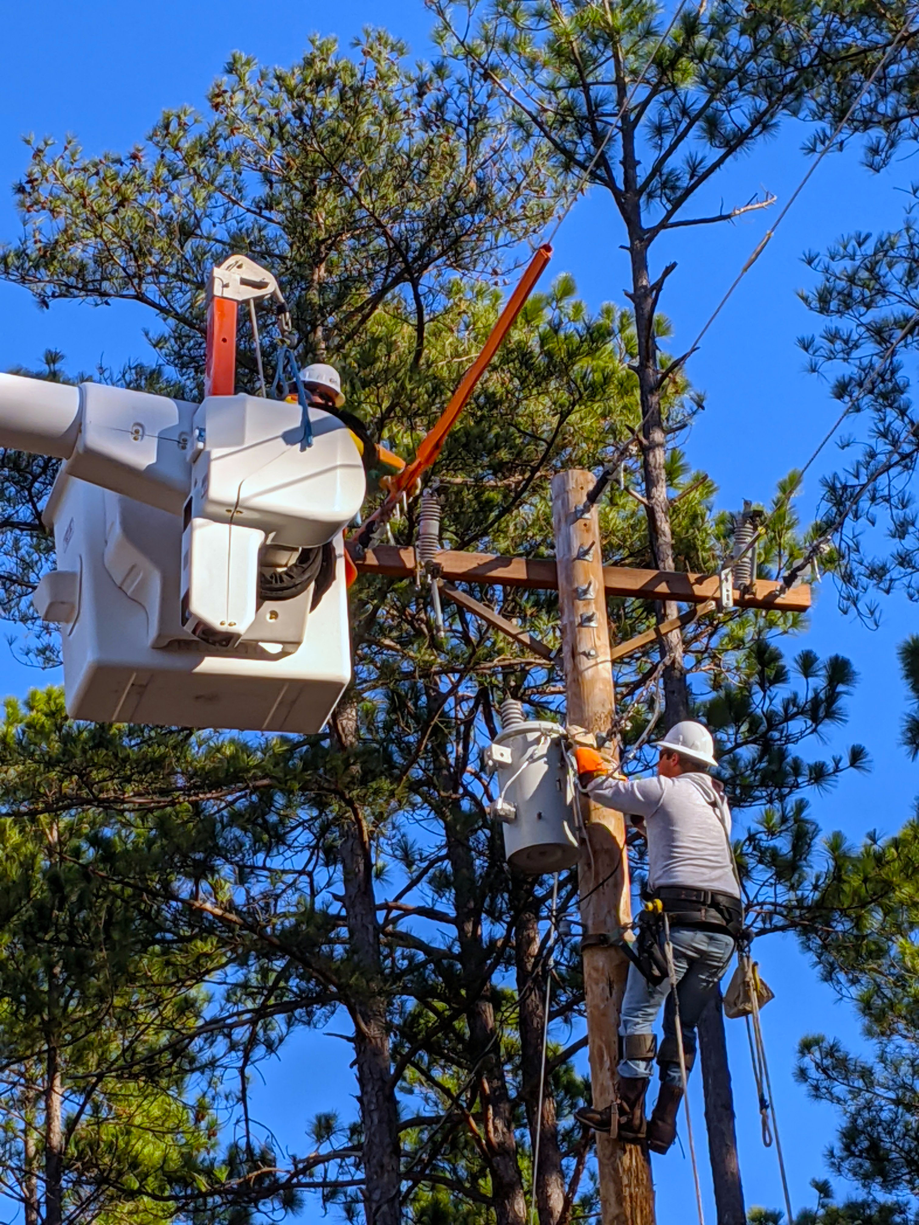 Lineman students work from a bucket truck and on the pole