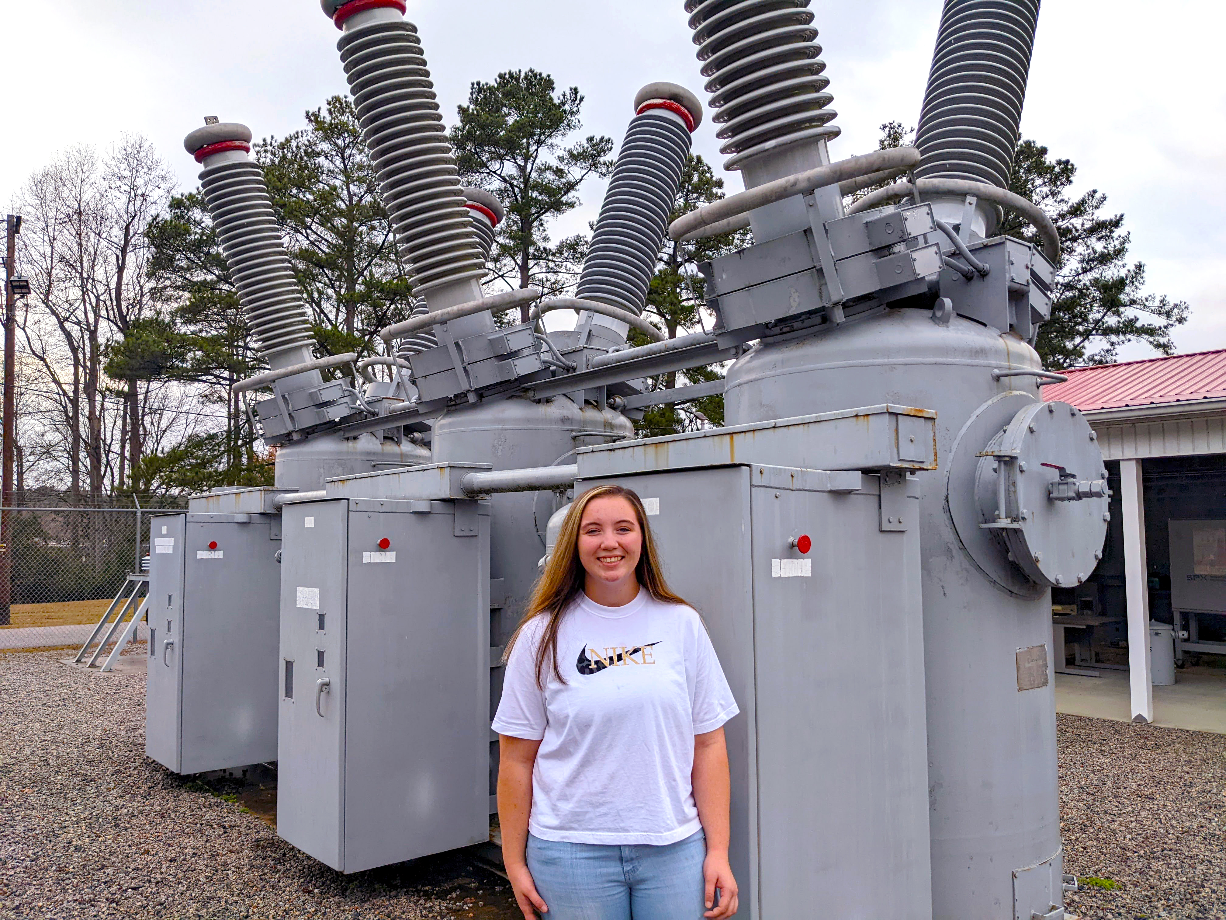 Meredith Standridge stands next to a large transformer unit