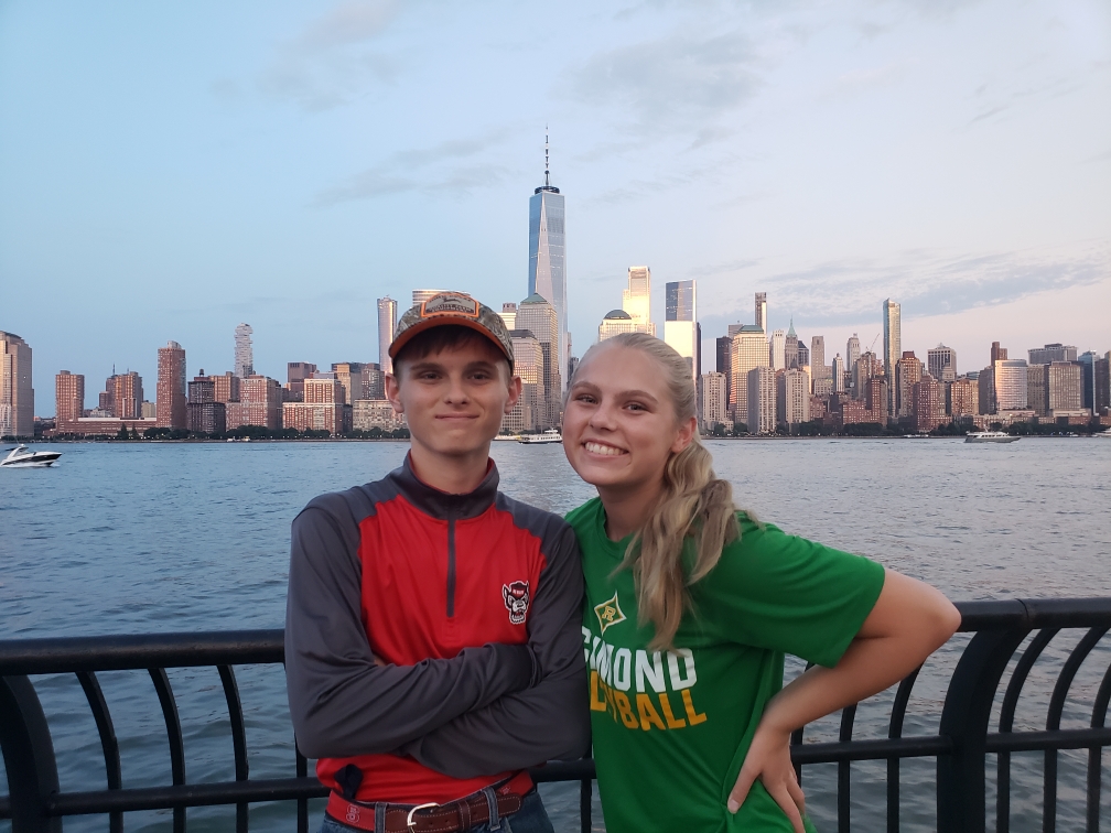 Evan and Emy Cooley stand for a photo with the NY skyline in the background
