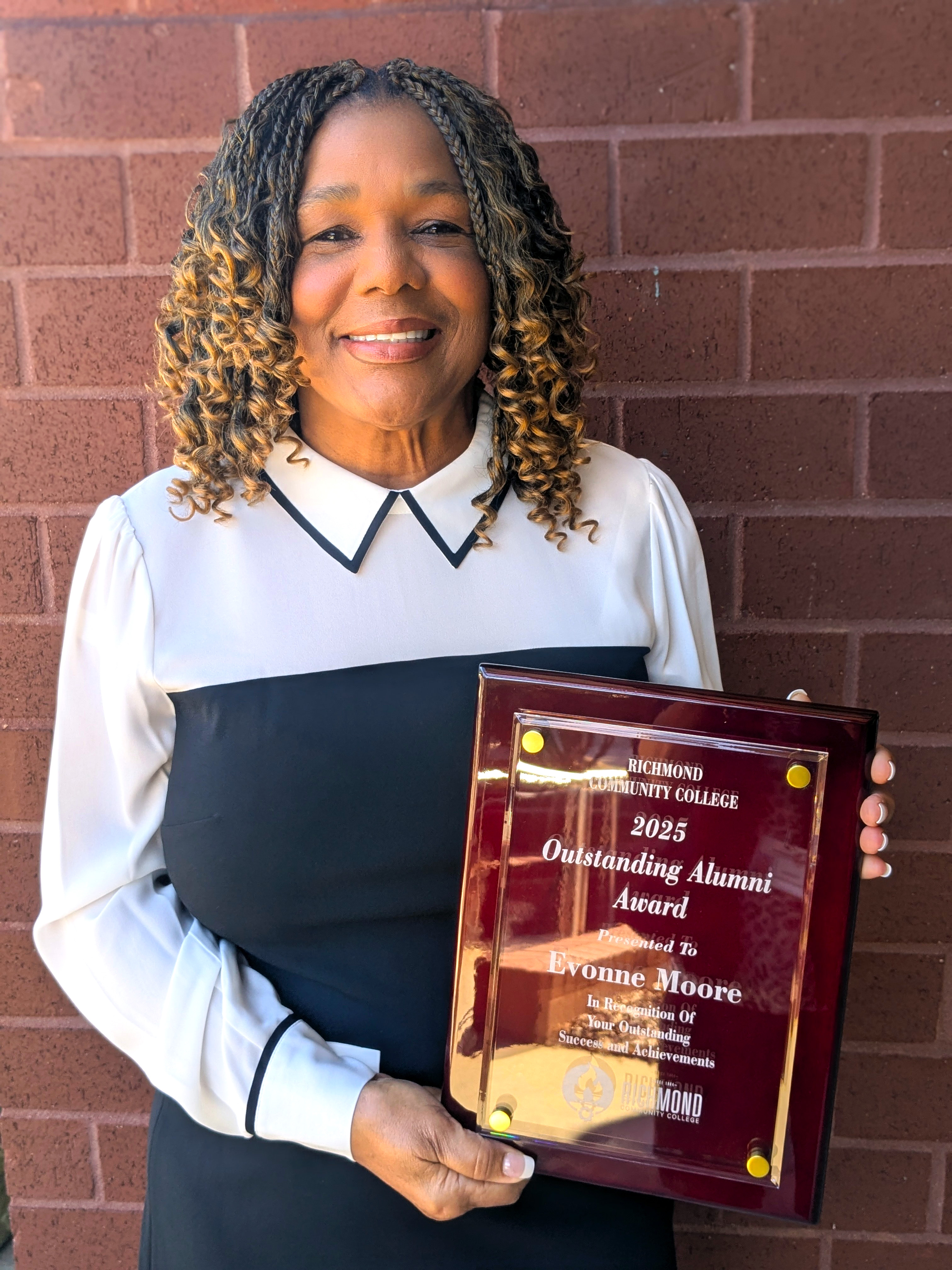 Evonne Moore holds her Alumni of the Year Award