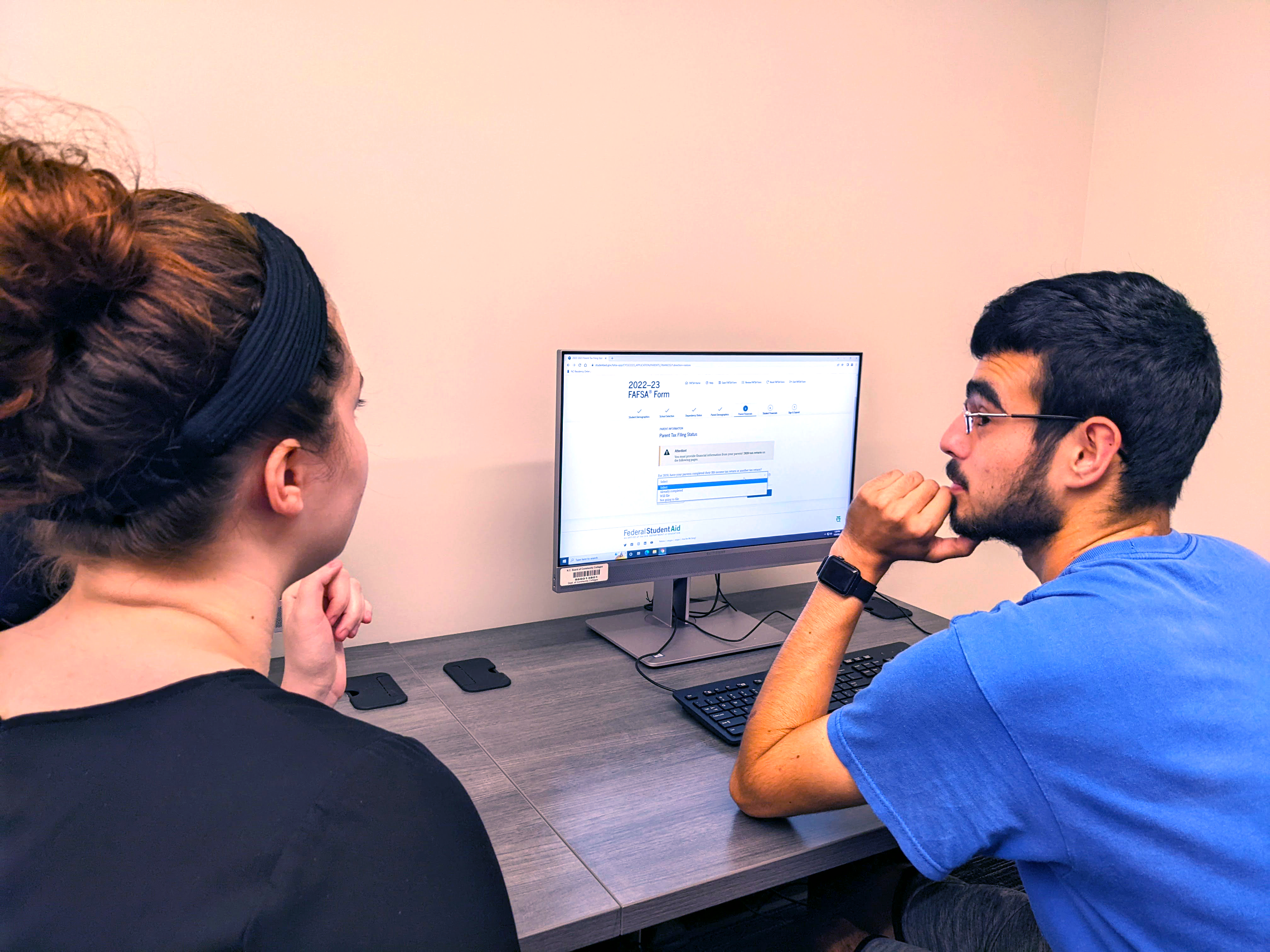 A financial aid staff member helps a student applying online