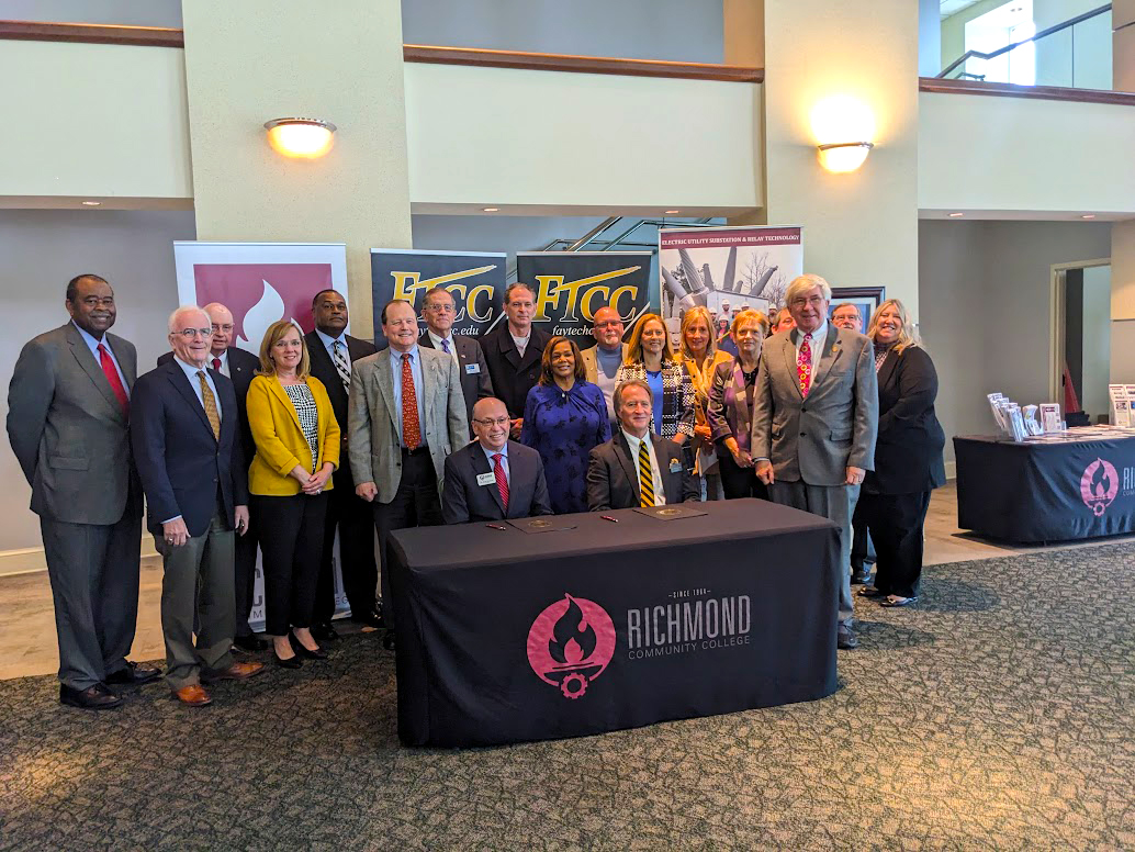 A group of college leaders and community leaders stand for a photo