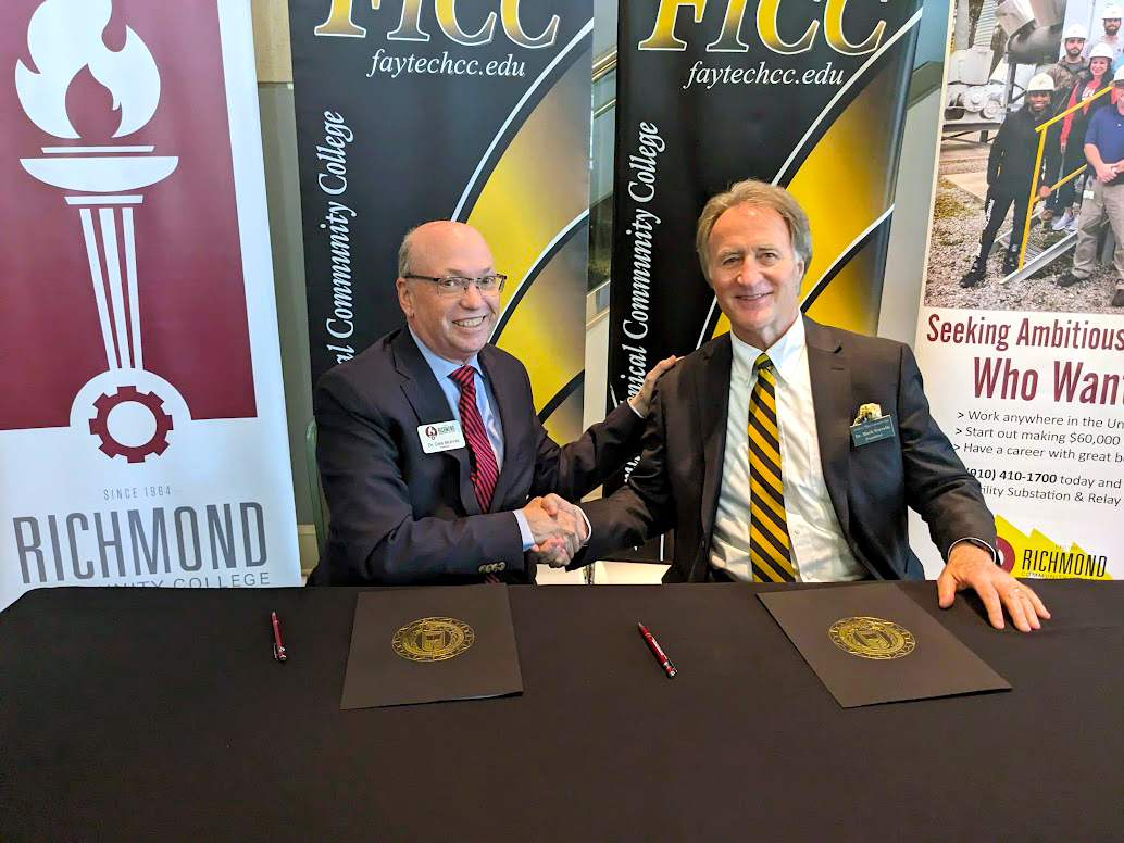 Dr. McInnis and Dr. Sorrells shake hands at a table.