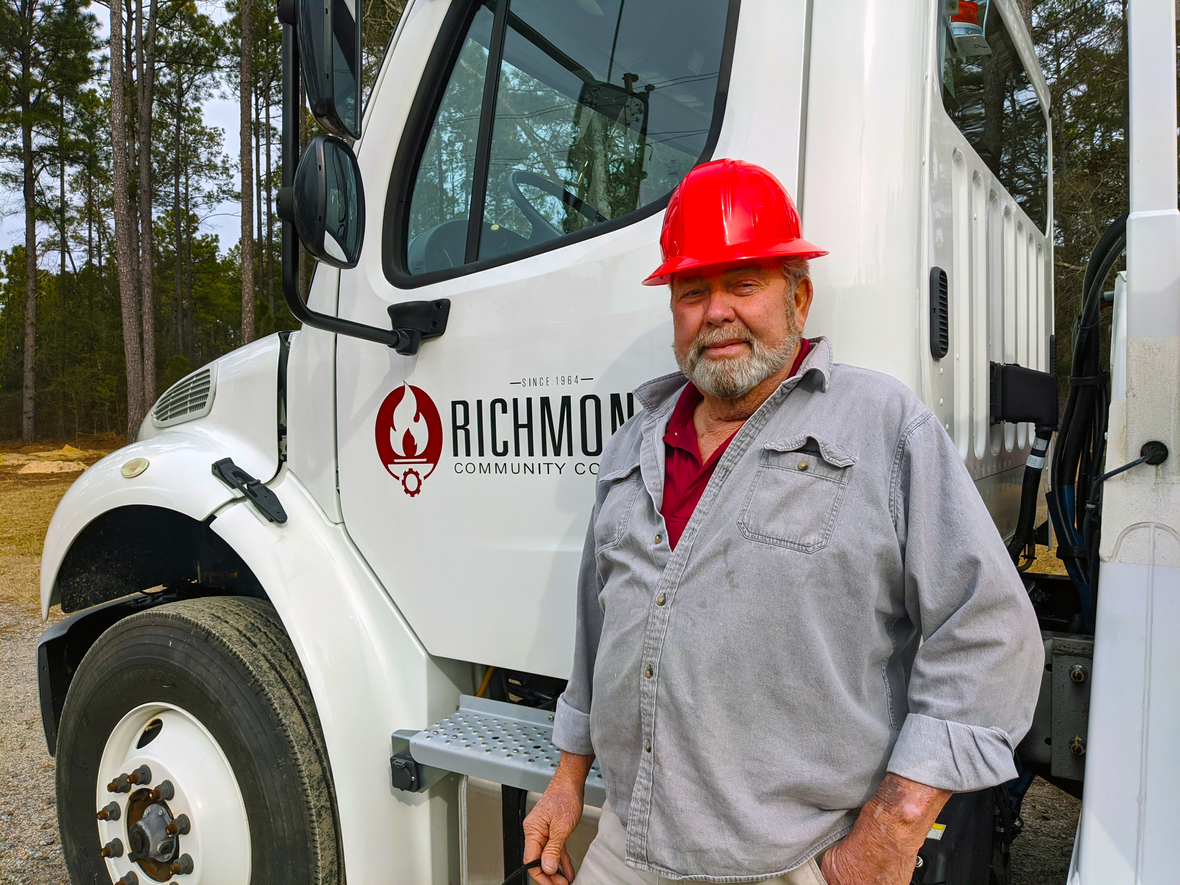 Lineman instructor Harold Rogers stands beside the bucket truck in the lineman yard.