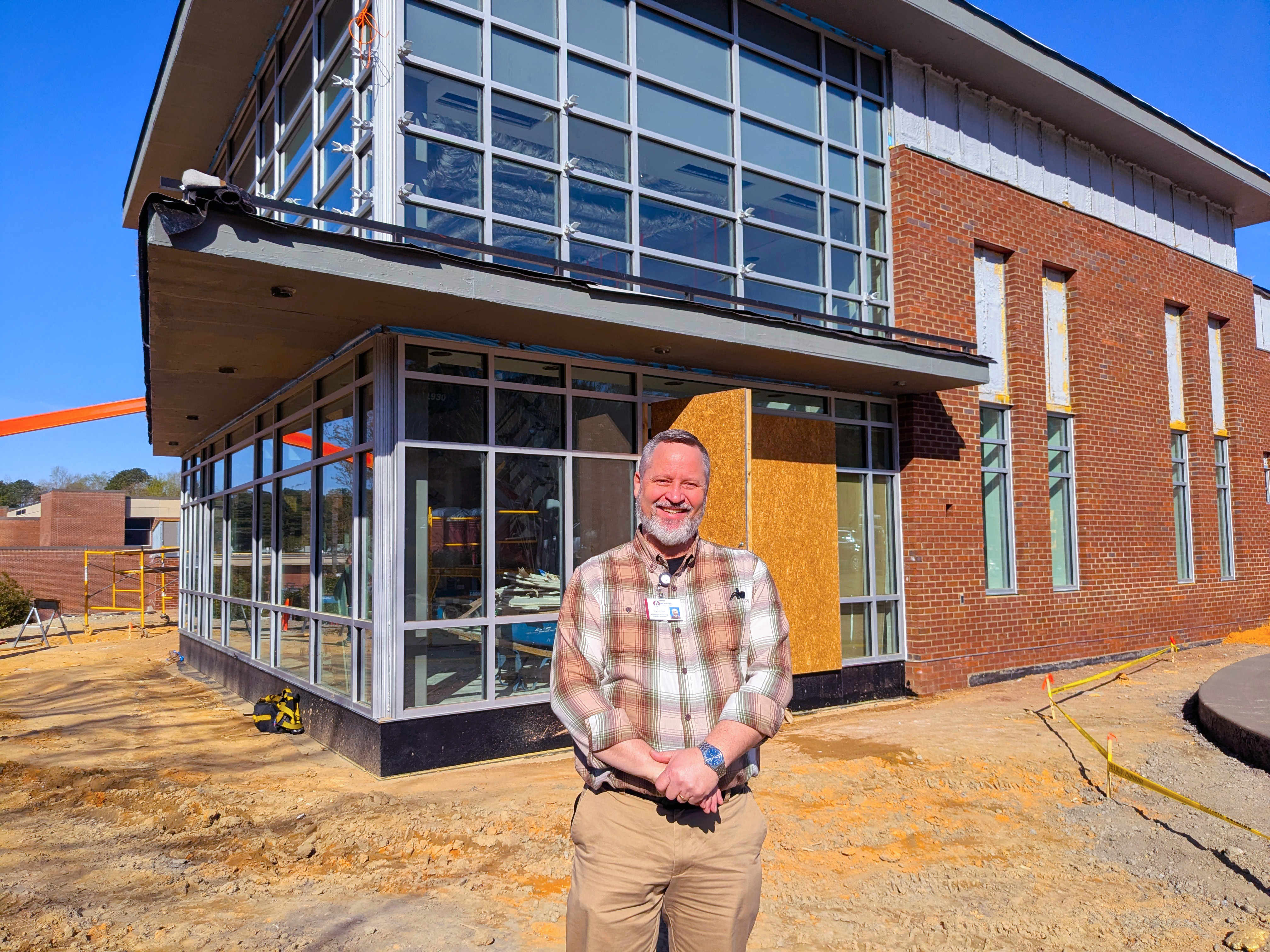 Larry Frye stands beside the Hendrick Center for Automotive Training, which is under construction.