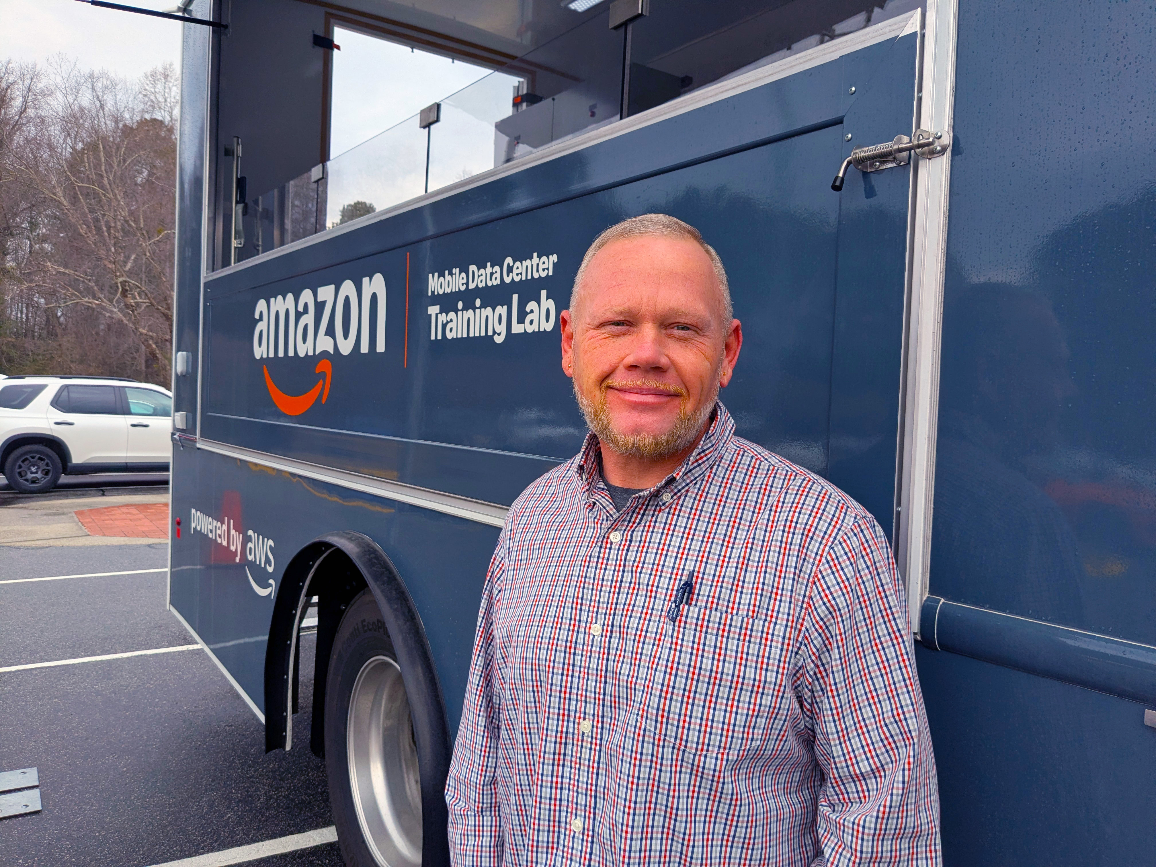 Jerrid Cade stands beside the Amazon Mobile Data Center Training Lab.