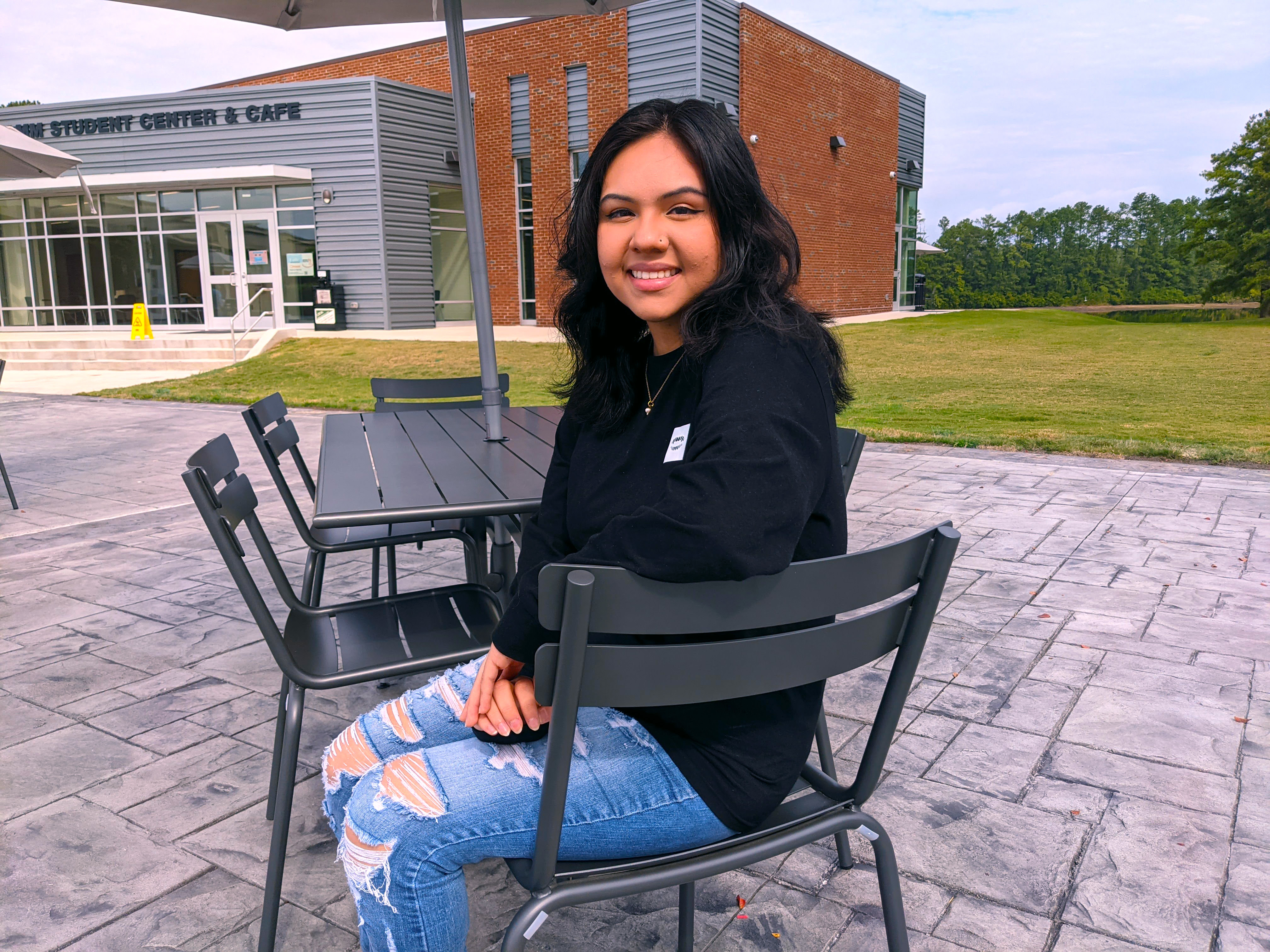 Jessica Santos sits at  table on the new patio in front of the RichmondCC Cafe