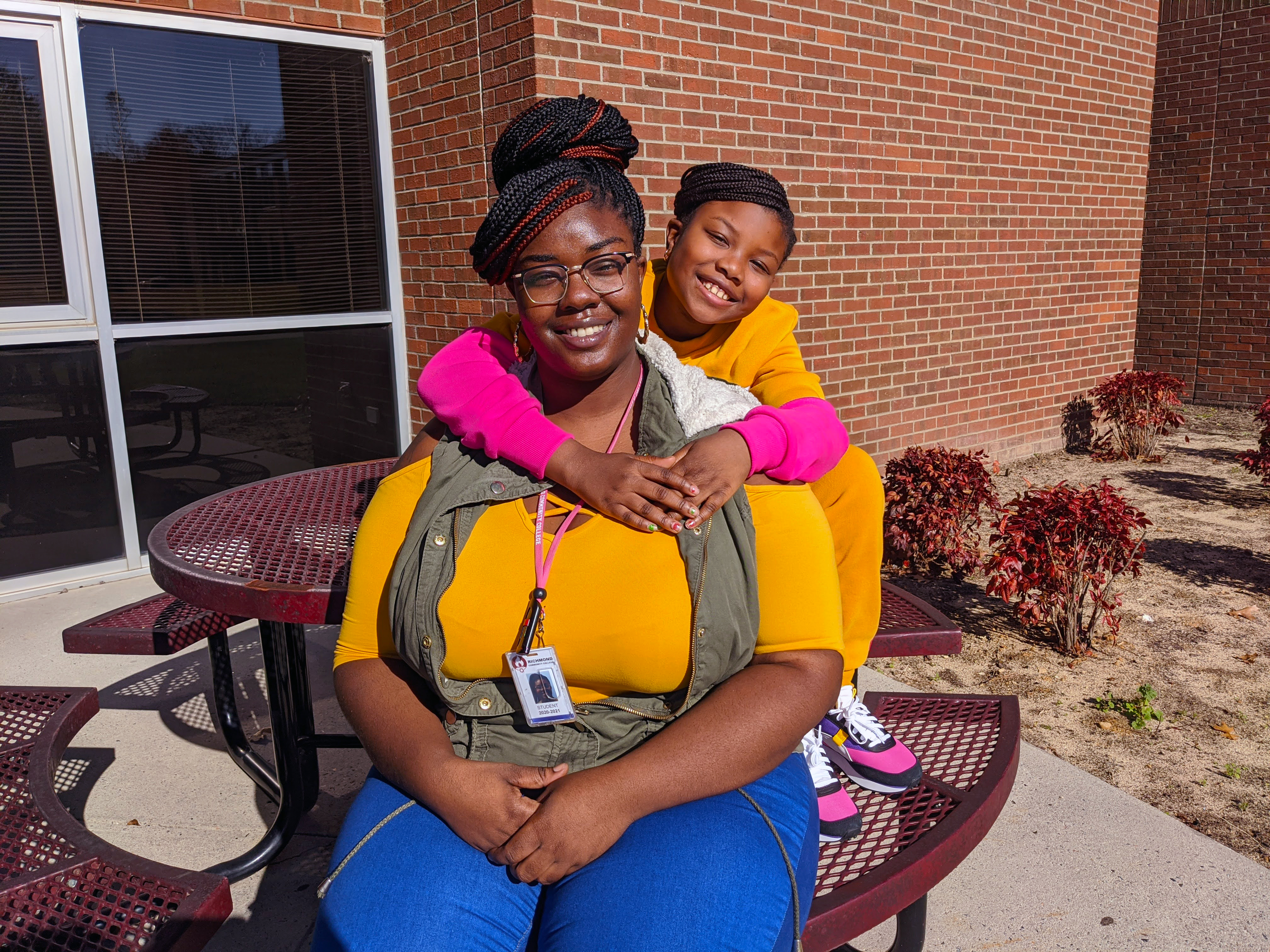 Latecia Smith and her daughter, Sanira, sit on a bench outside a building at RichmondCC.