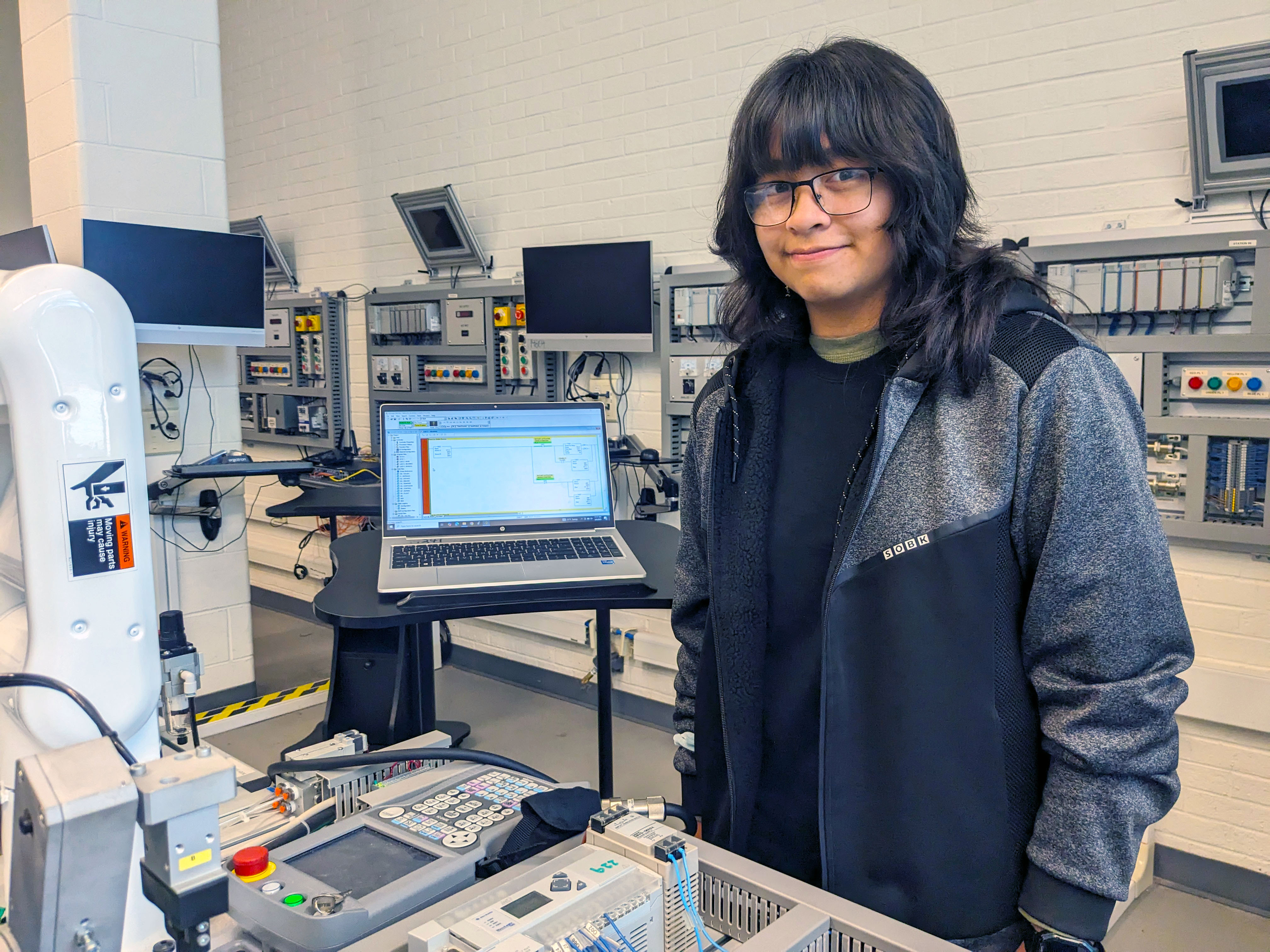 Mechatronics student stands in Automation Lab.