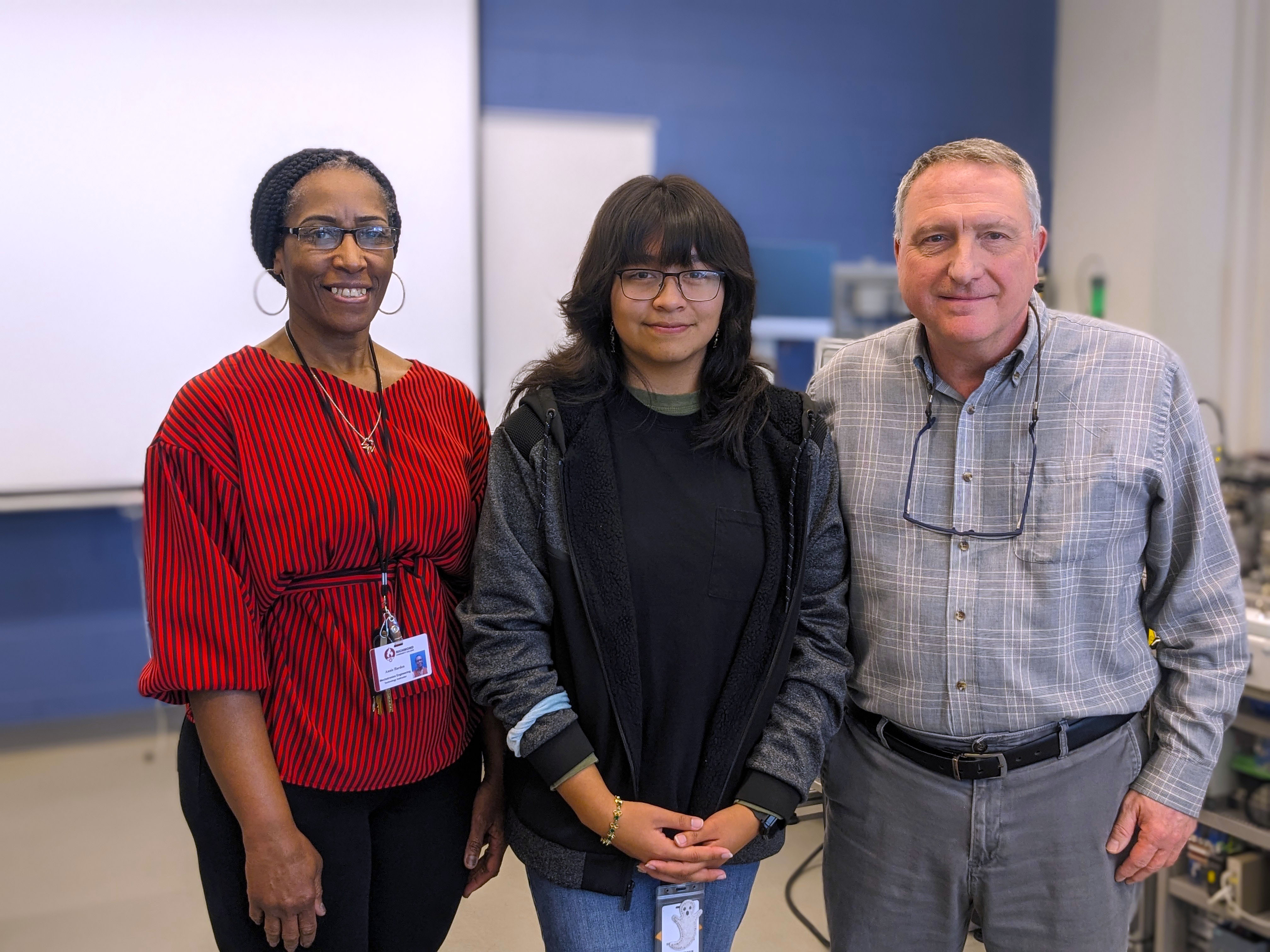 Ellen stands with her instructors in the Mechatronics Lab.