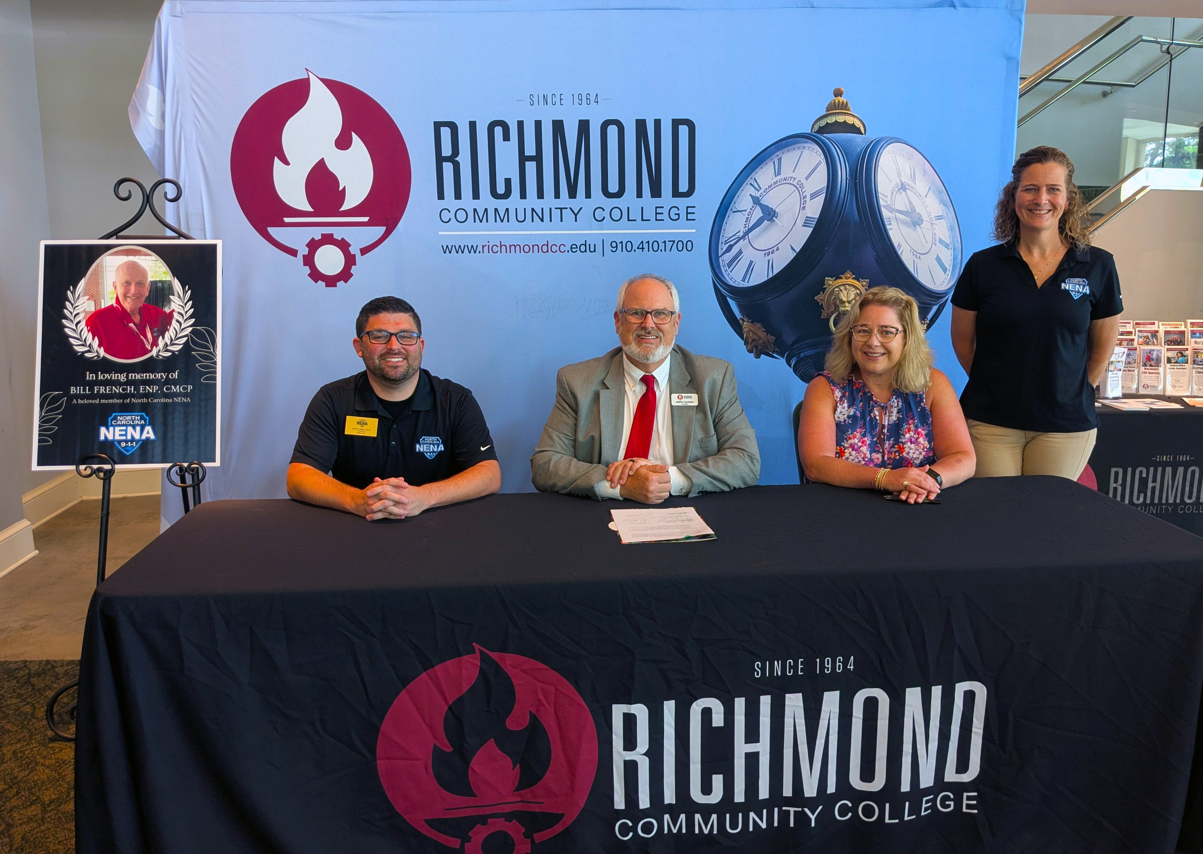 College leaders and 911 leaders sit at table signing a scholarship