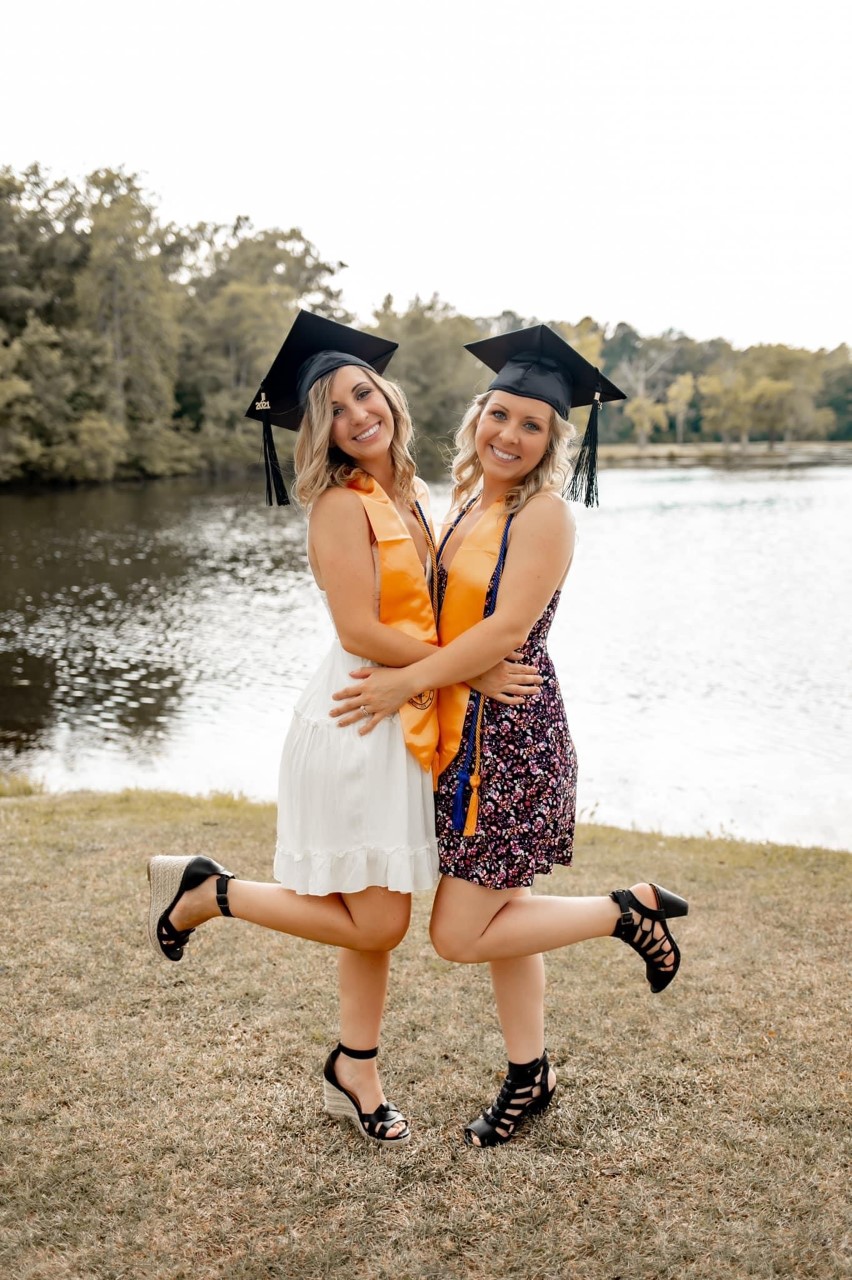 Brooke Odom and her sister, Jessica Tarlton, pose in their graduation caps.