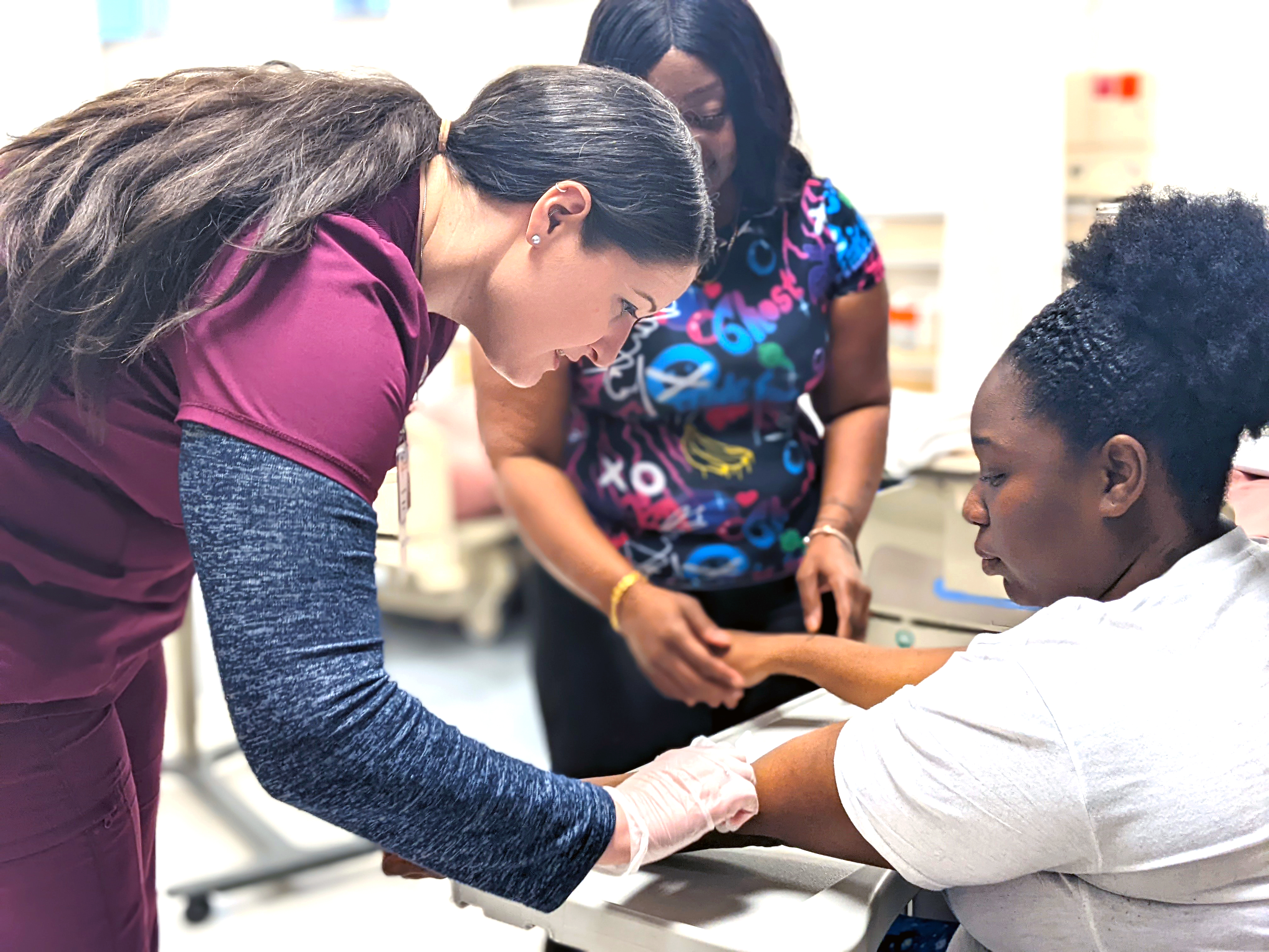 A phlebotomy instructor demonstrates how to draw blood.