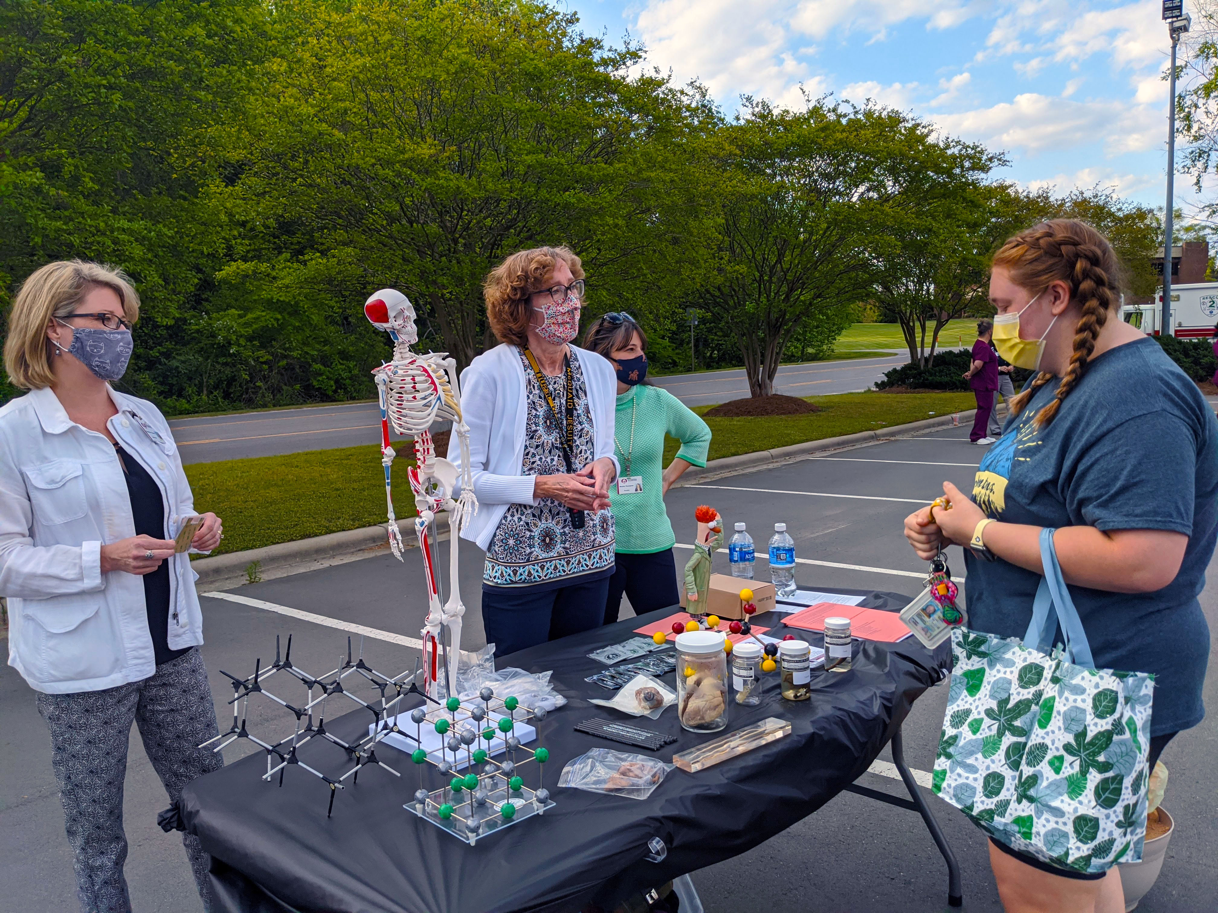 Science instructors stand at a table talking to a prospective student at the Program Fair.