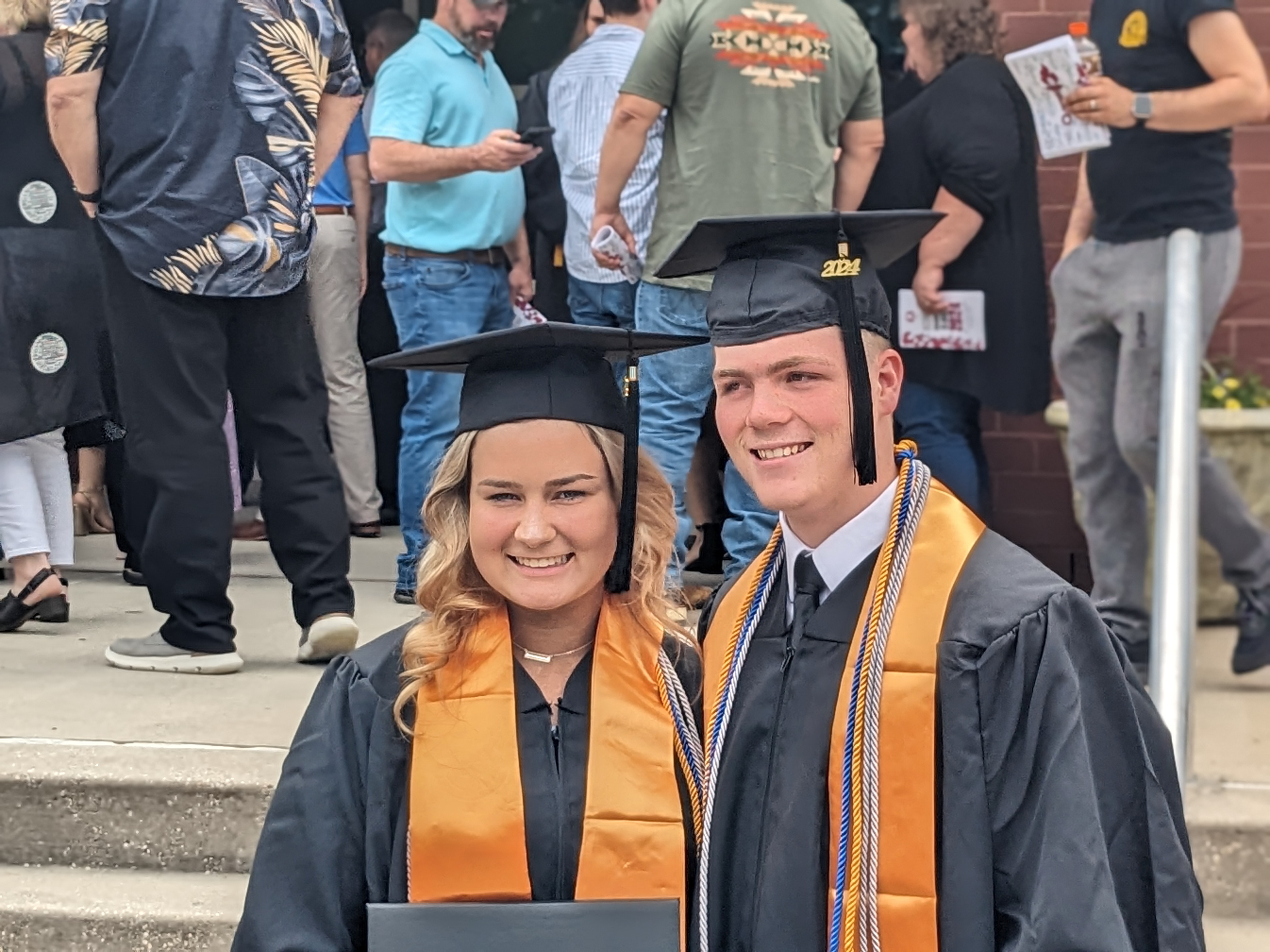 Two graduates pose for a photo.