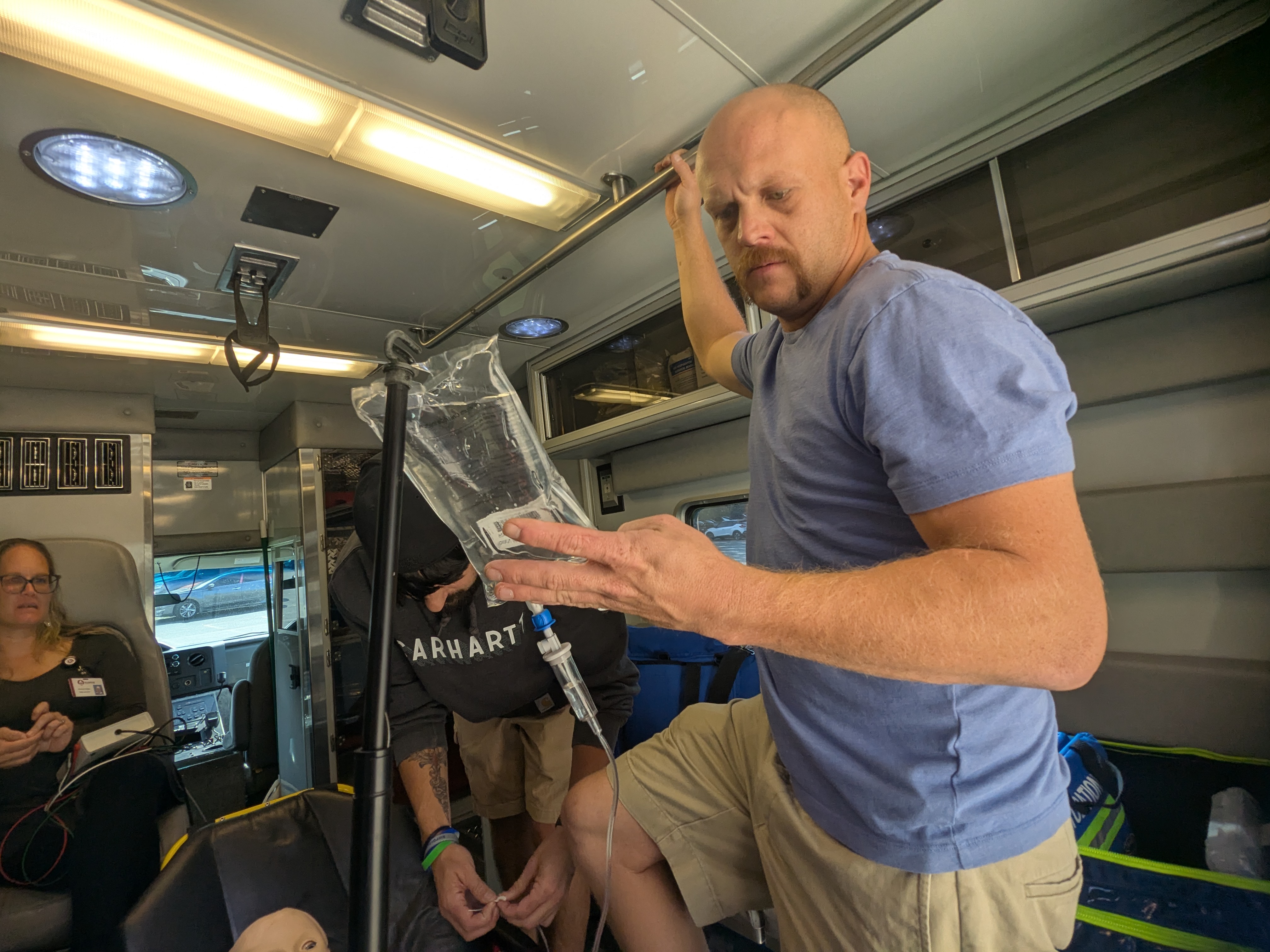 Paramedic student looks at IV bag in back of ambulance.