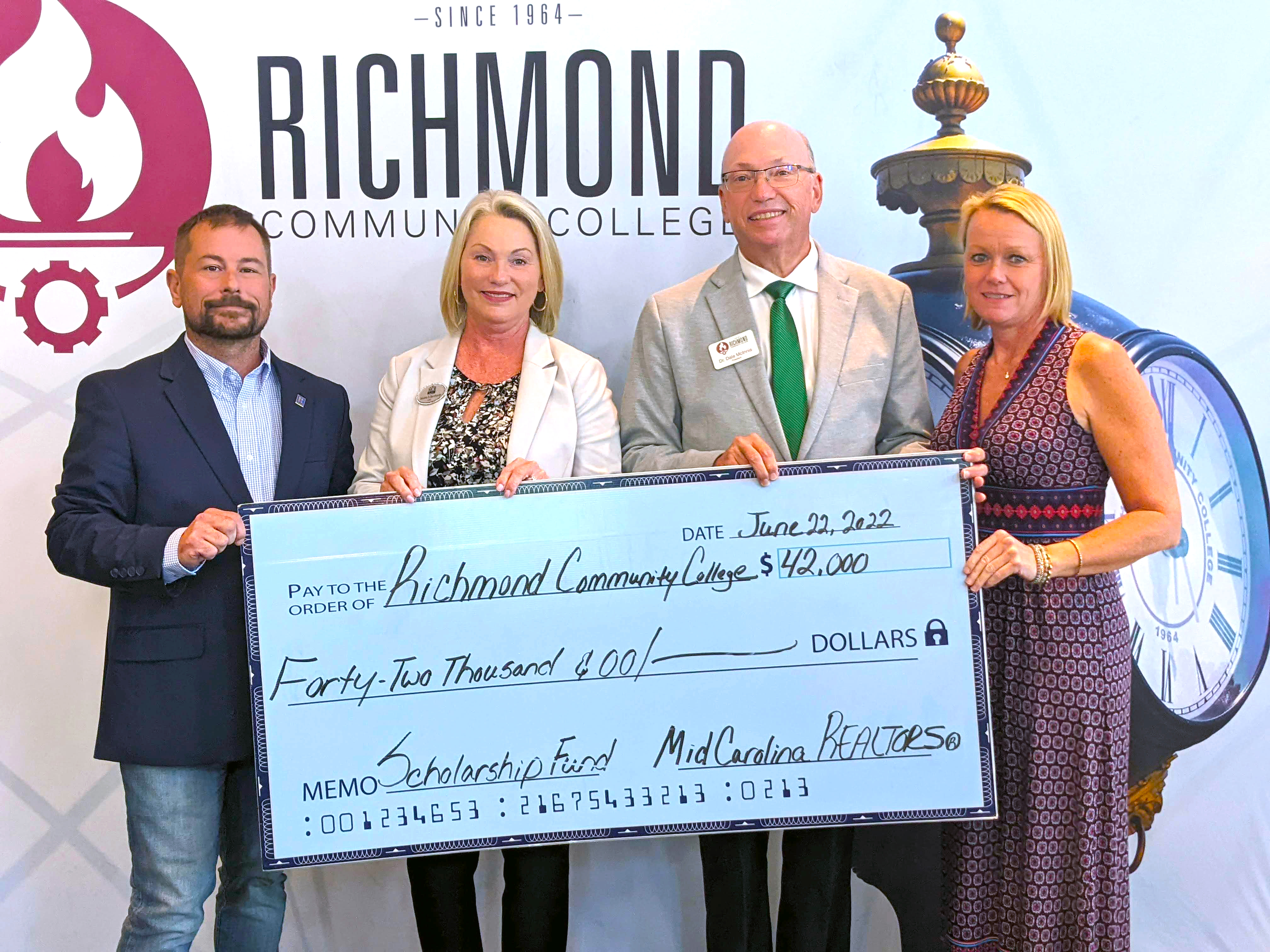 Realtors stand with College President holding a big check