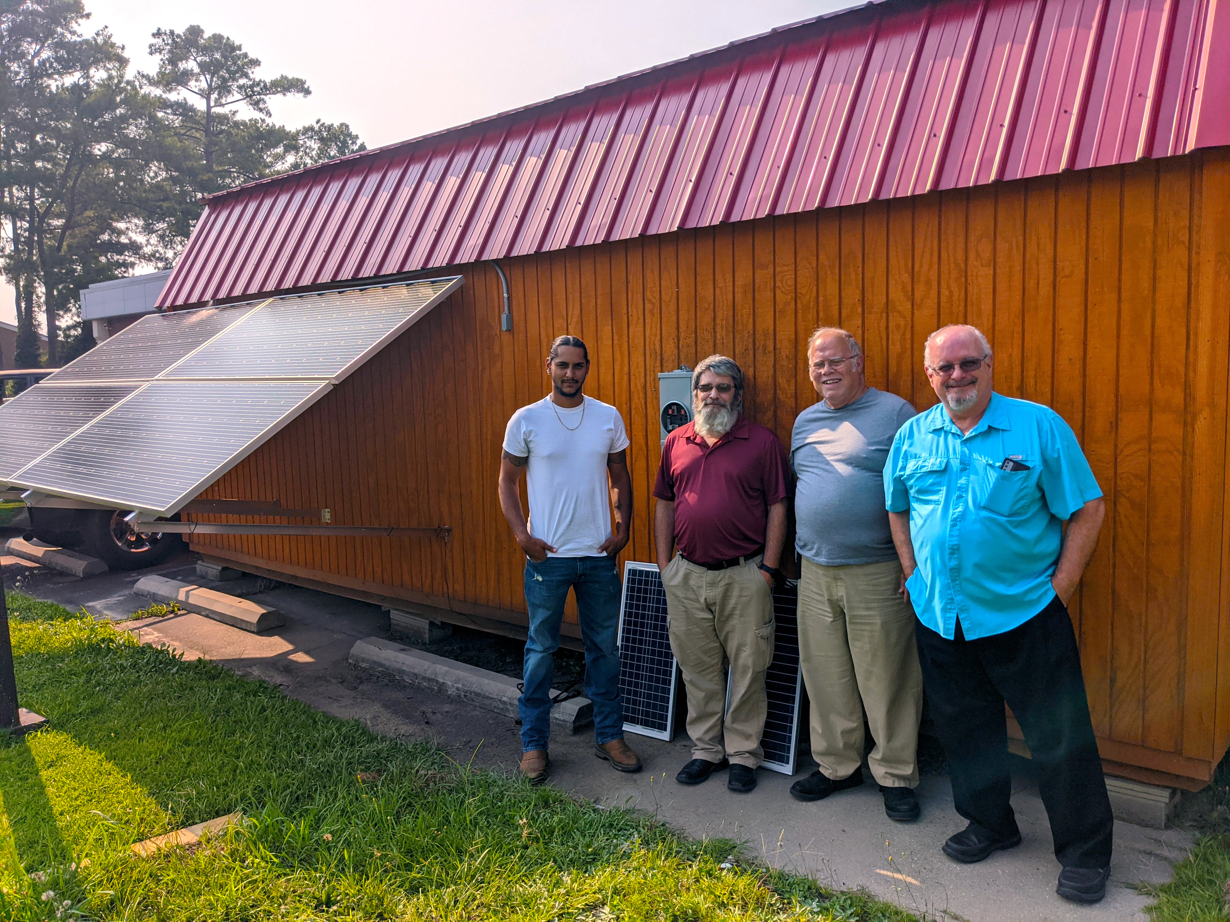 Students and instructor stand next to the solar shed