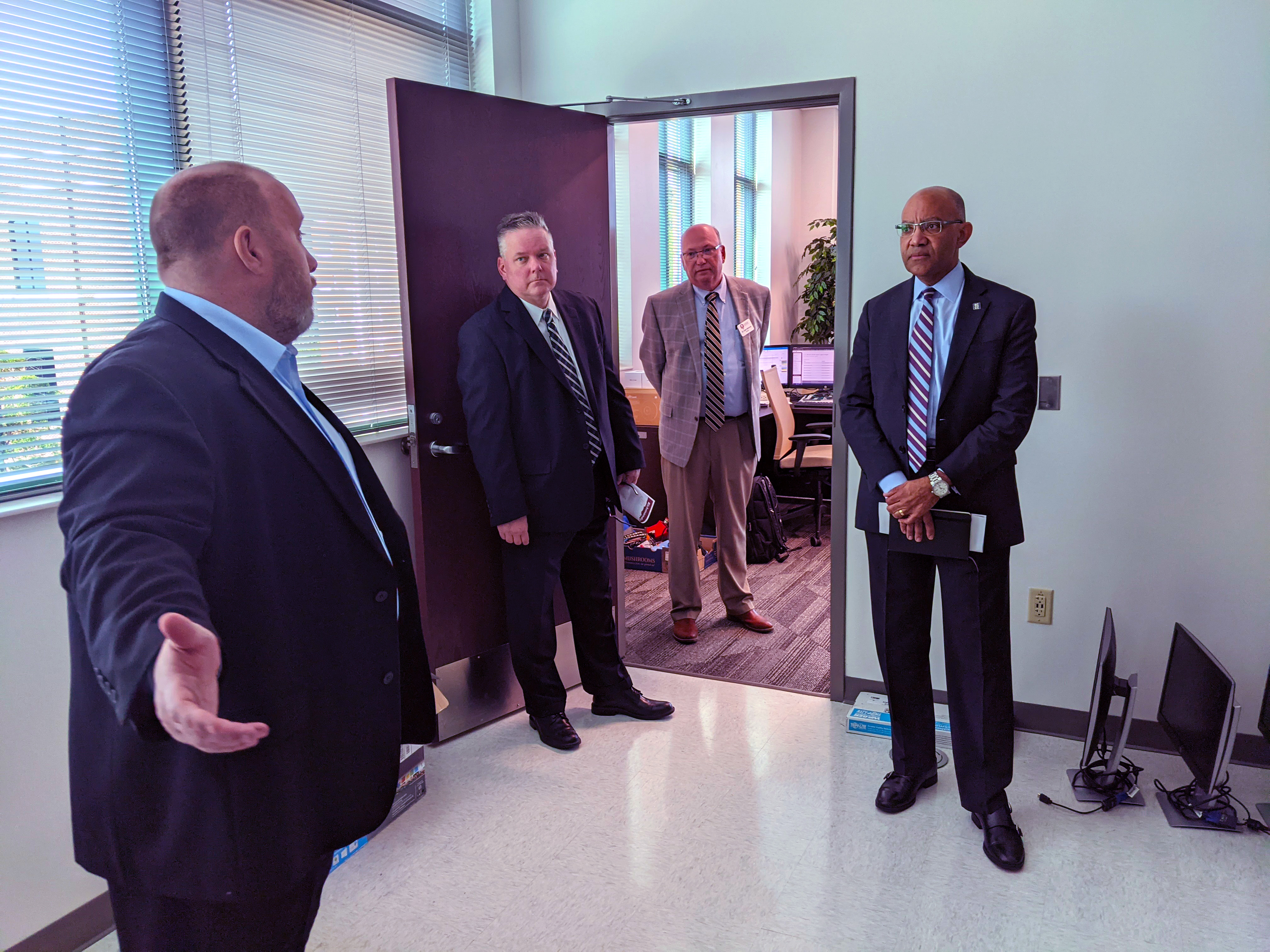 Instructors stand with president in classroom.