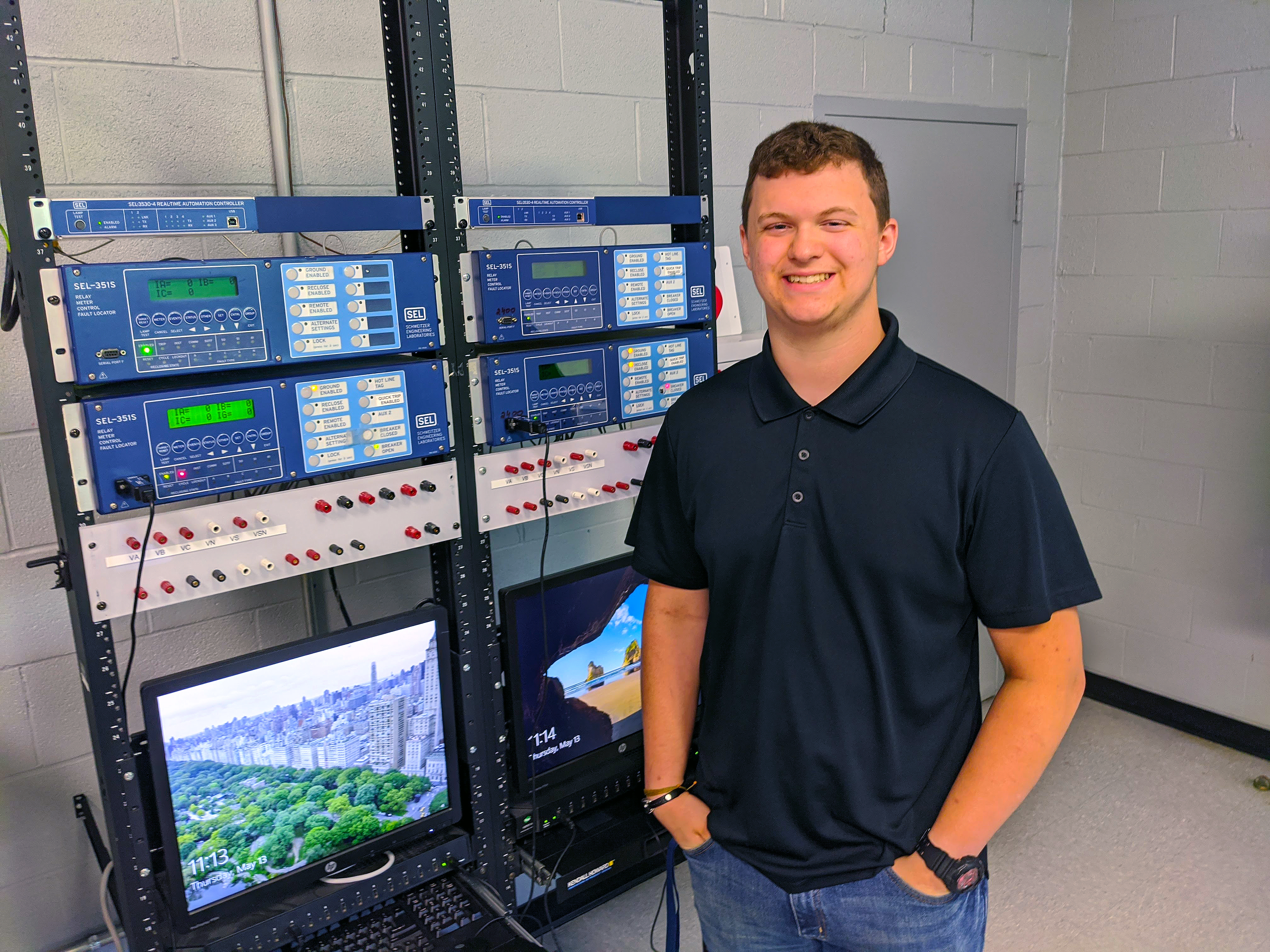 Student stands beside a bank of relay systems