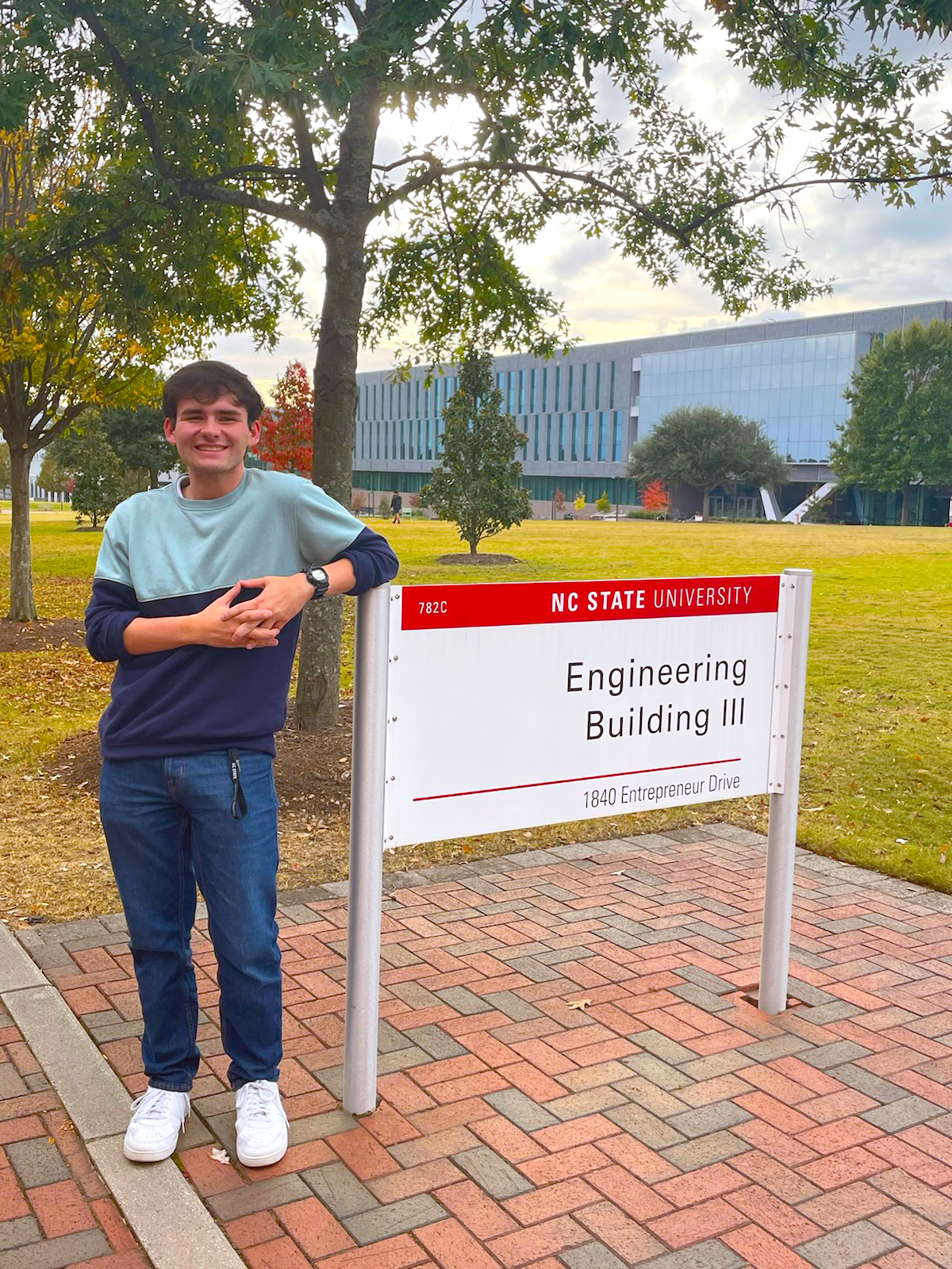 Joel Dunn stands by a sign on the campus of NCSU
