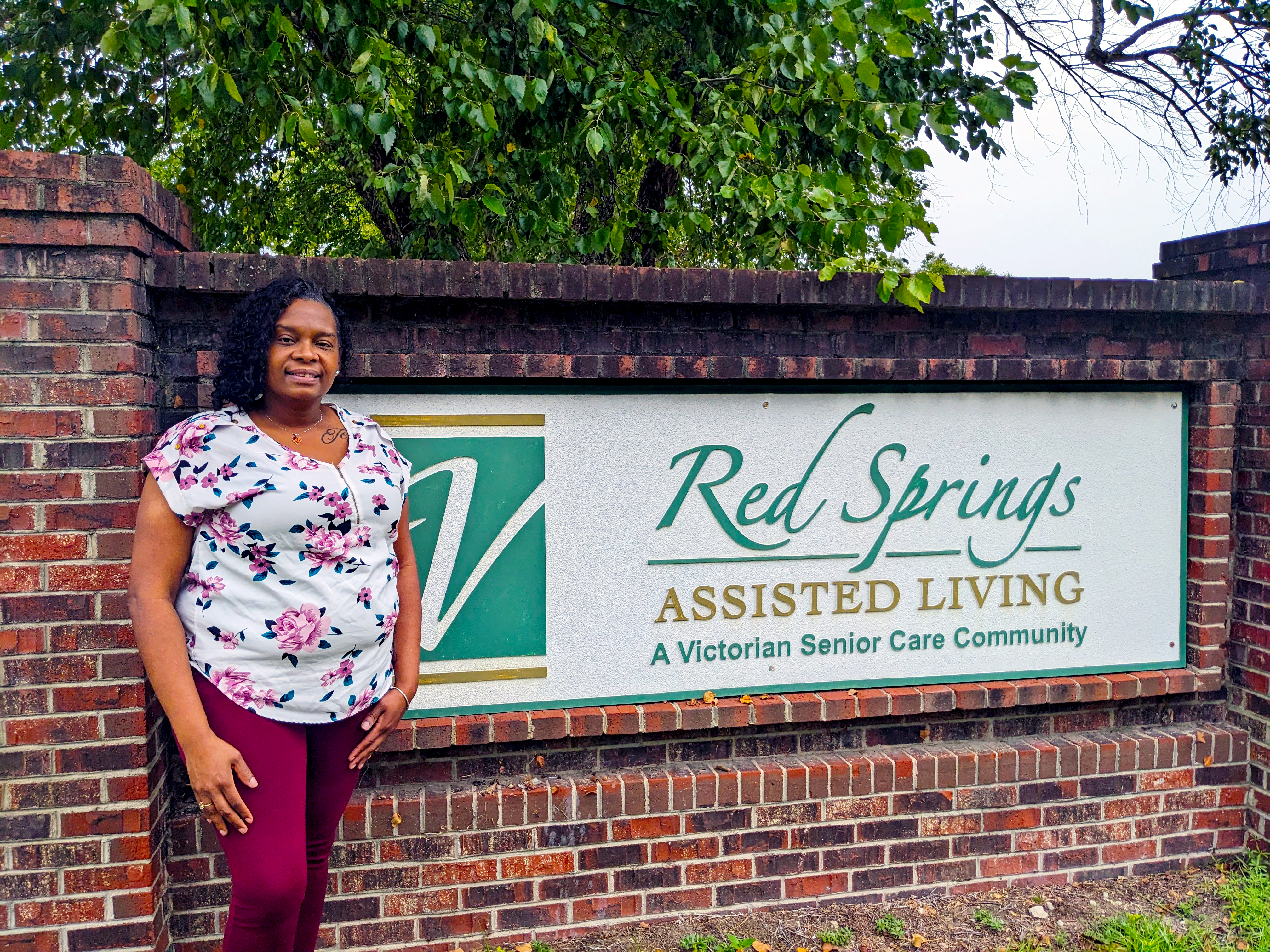 Tonja McPhaul stands by building sign for Red Springs Assisted Living