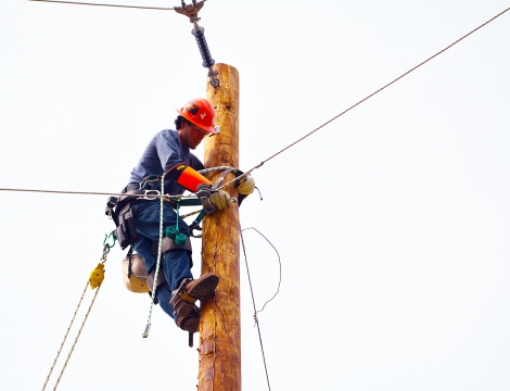 Lineman student climbing up a pole working on a power line