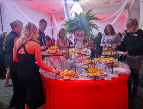 Photo of people in formal attire making plates of food at the Gala