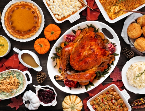Table of thanksgiving food including a turkey at the center