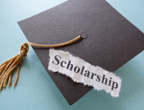 Graduation Cap with a paper that reads "scholarship" on it
