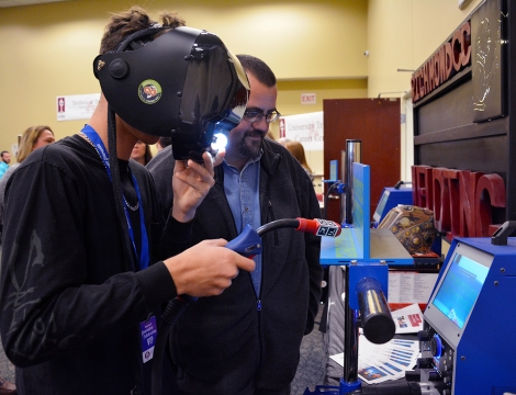 A young boy tries out the virtual welder at the Open House.