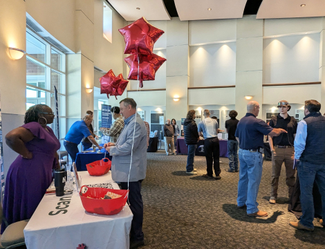Multiple students speaking with employers at booths at the Power the World Career Fair of Fall 2025